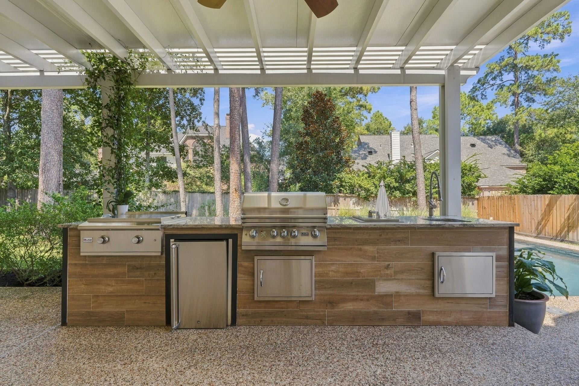 22 Hillside View Place, The Woodlands, TX 77381 The large covered outdoor living space features a complete summer kitchen offering a traditional grill, flat griddle
,refrigerator, and sink.
