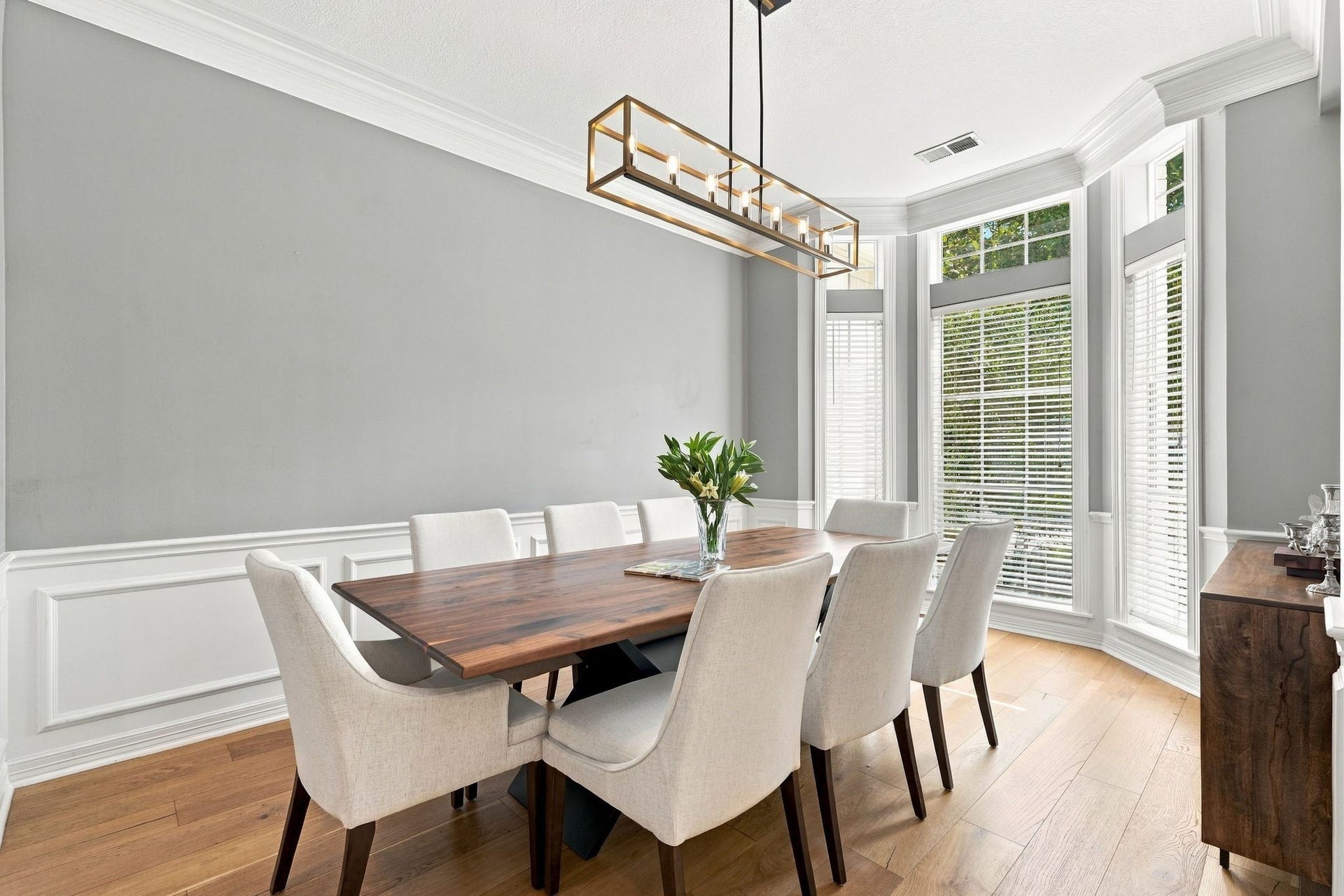 22 Hillside View Place, The Woodlands, TX 77381 The sophisticated formal dining room showcases extensive millwork, hardwood flooring, a contemporary light fixture, and bay windows bringing that bring in plenty of natural light.