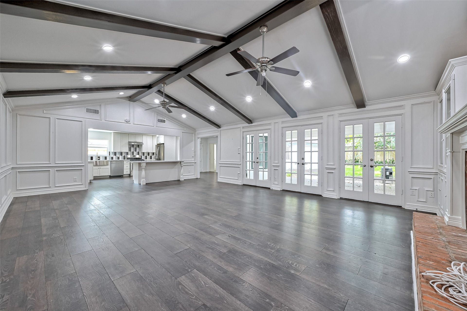 Large family room features high ceiling, 2 ceiling fans, fire-place, build in glass window cabinets, open to kitchen.