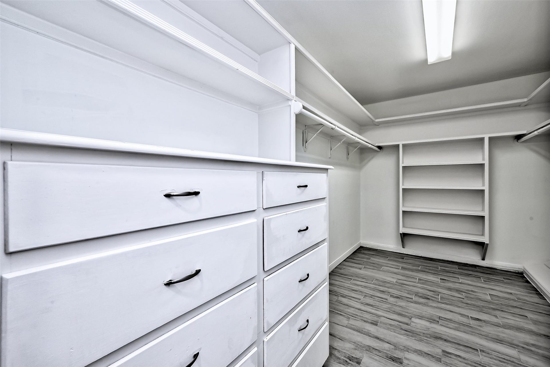 Primary walk in closet with build in dresser and shelf