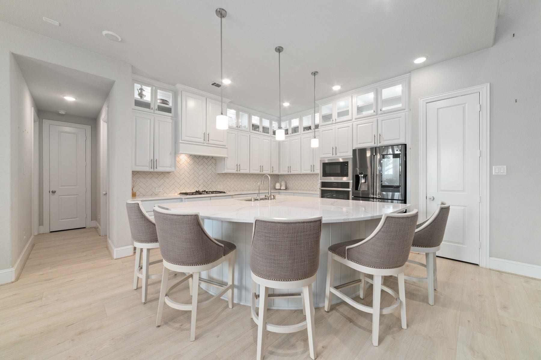 A spacious island with seating, and modern pendant lighting.