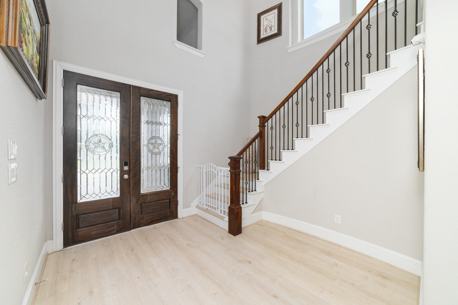 The entryway featuring a grand staircase with wrought iron railings.