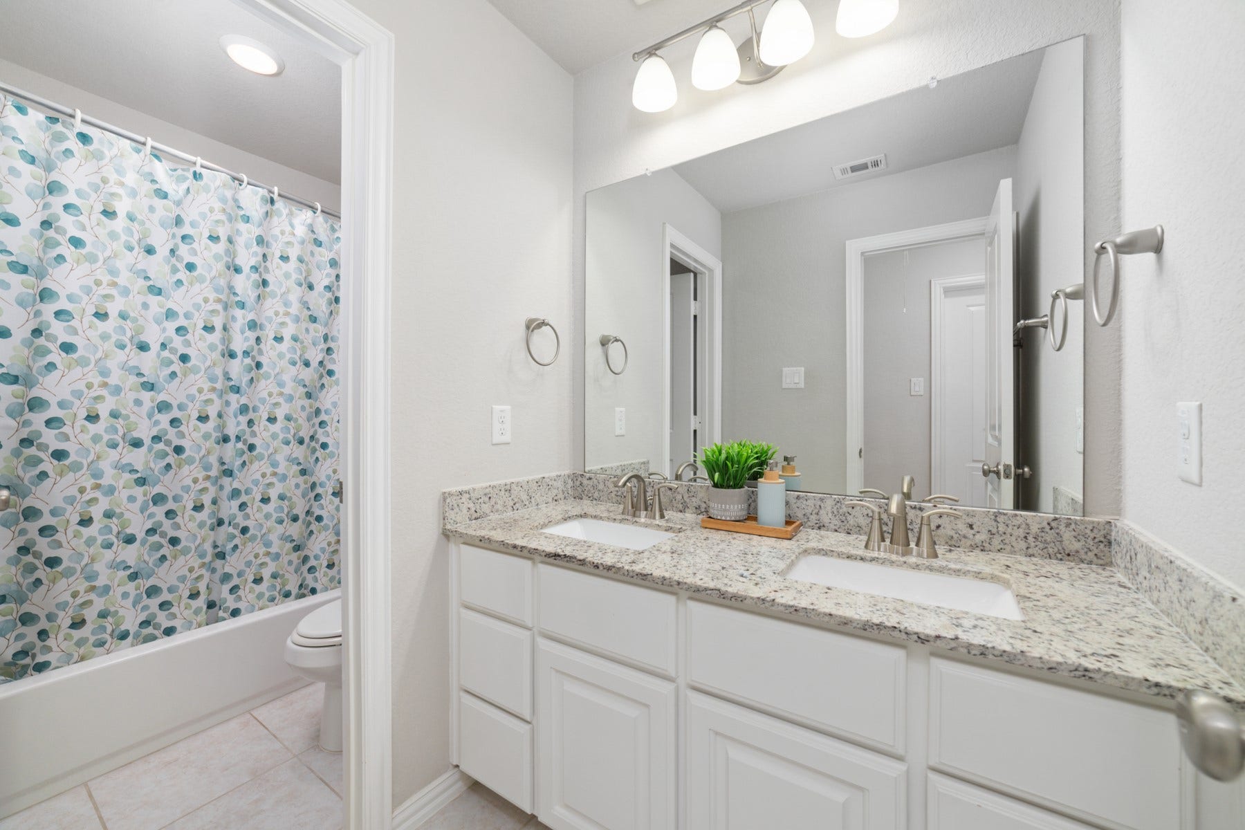 Bright and modern bathroom featuring a double vanity with granite countertops.