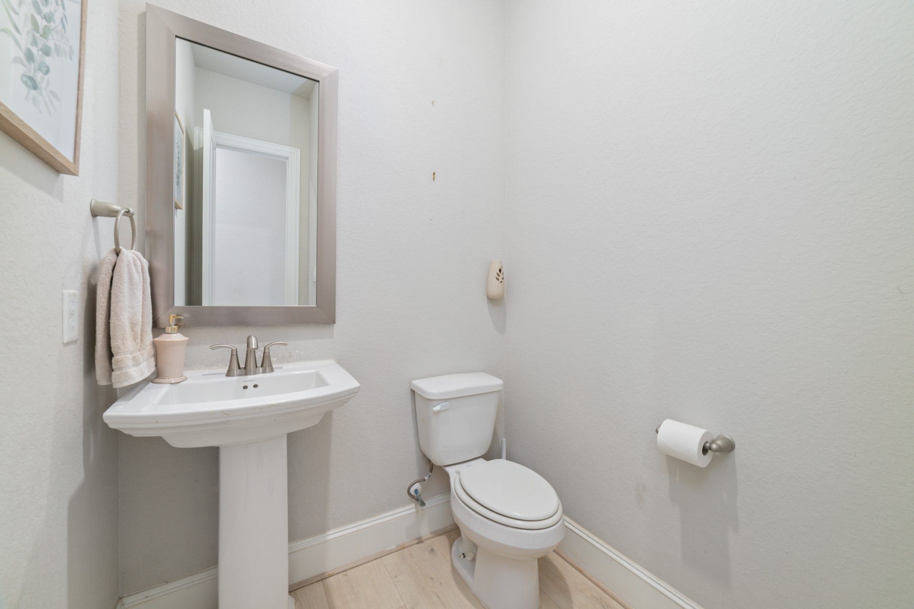 Elegant half-bathroom with a pedestal sink, and a neutral color palette.