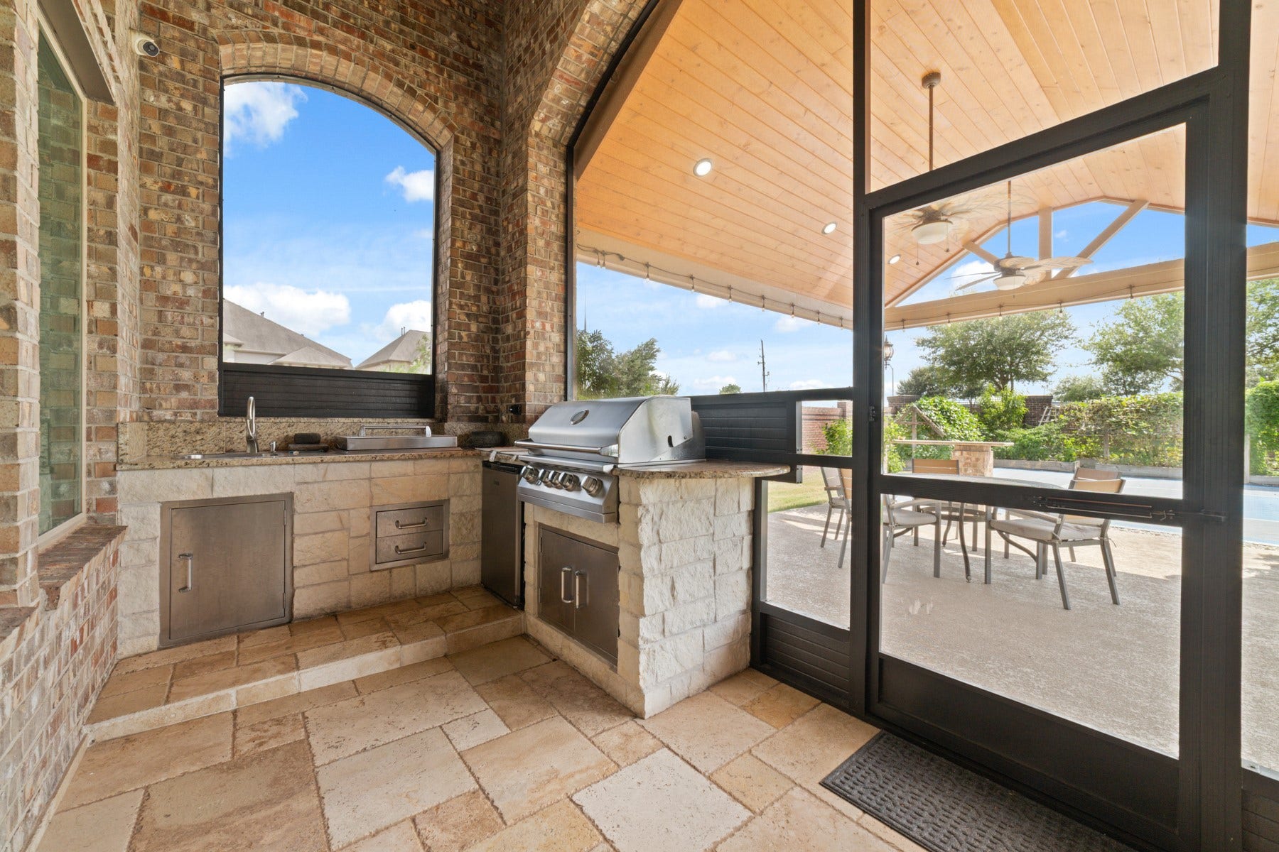 Experience outdoor living at its finest with this stunning covered patio featuring a built-in grill.