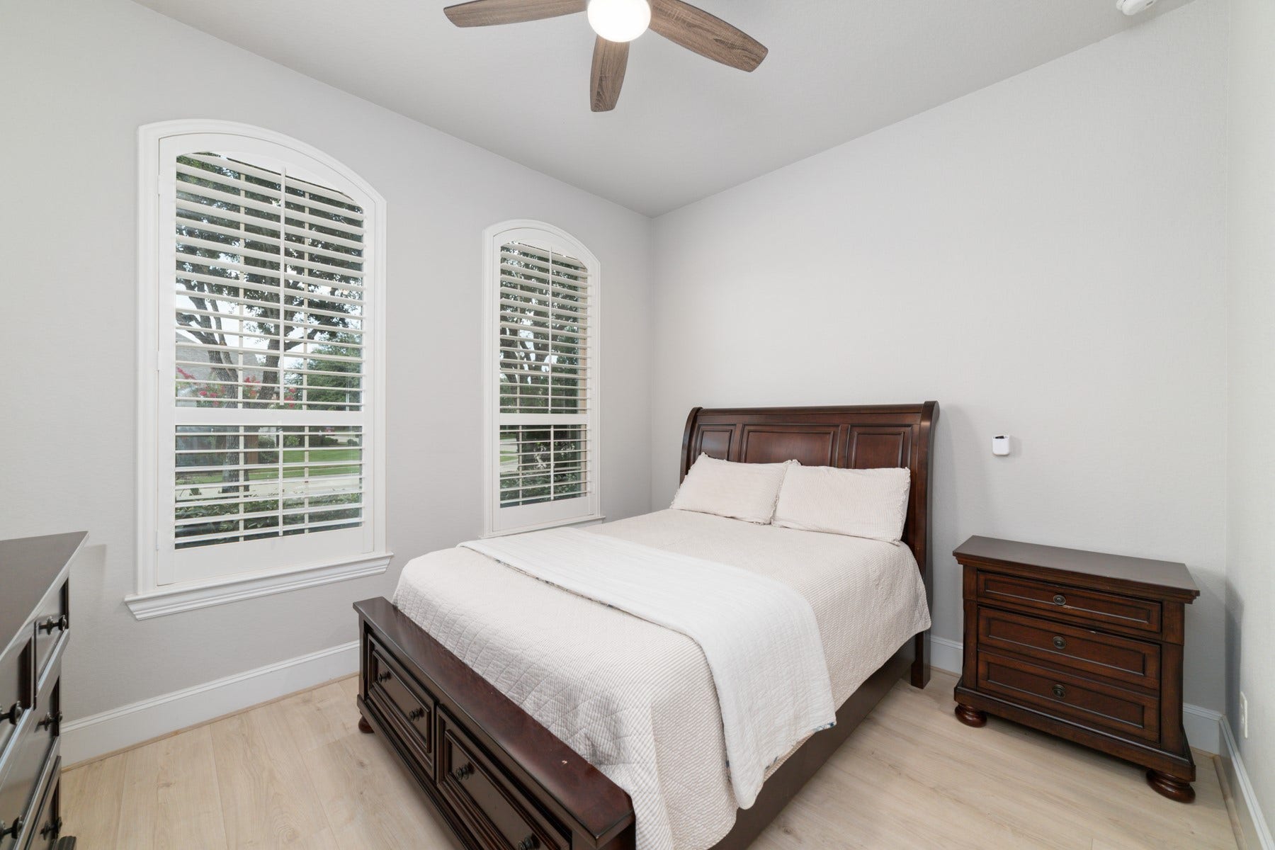 Cozy bedroom featuring large windows with plantation shutters.