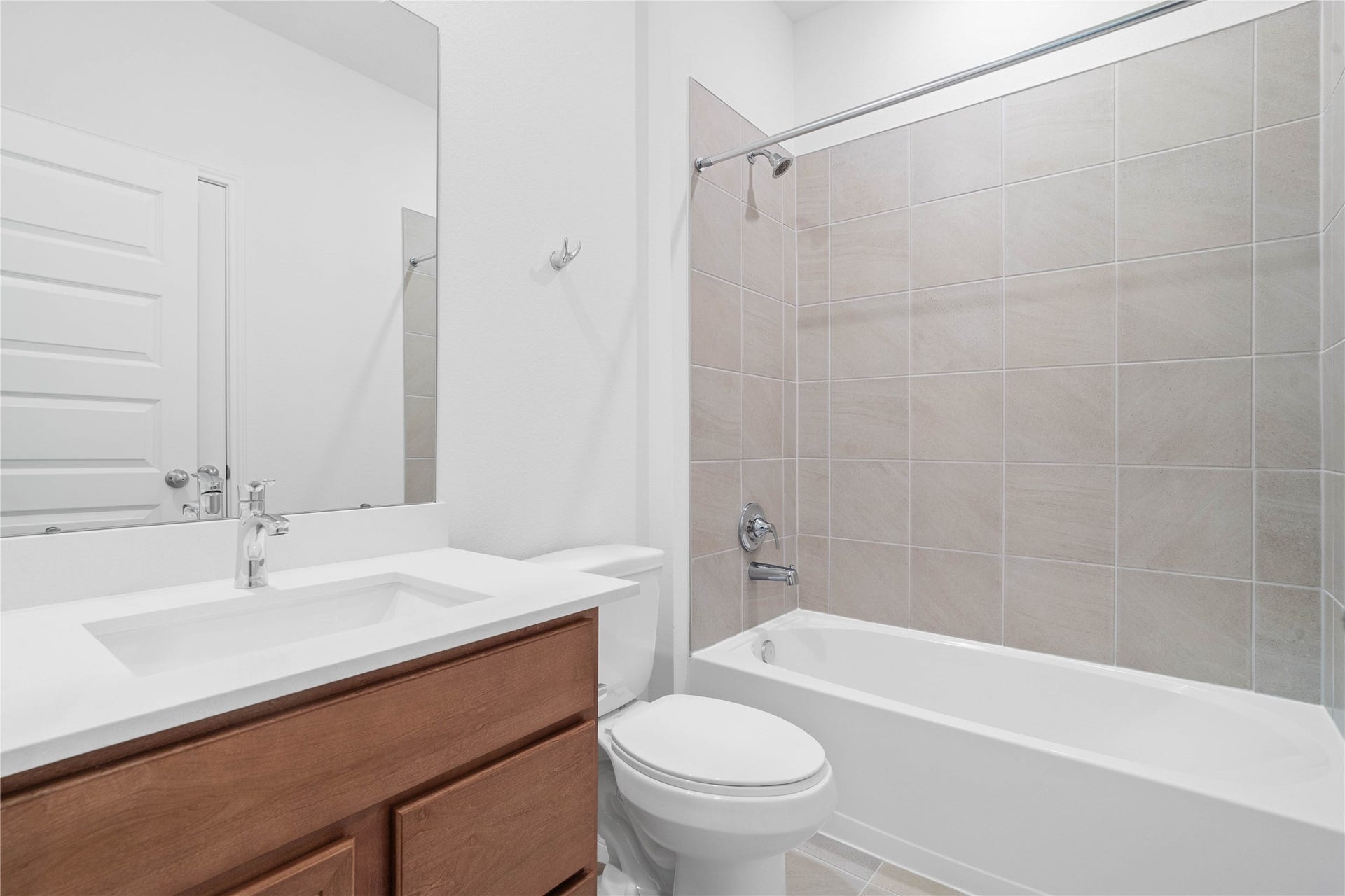 640 Appaloosa Meadow Drive, Magnolia, TX 77354 Secondary bath features tile flooring, tub/shower combo with tile surround, stained wood cabinets, beautiful light countertops, mirror, sleek fixtures and modern finishes.