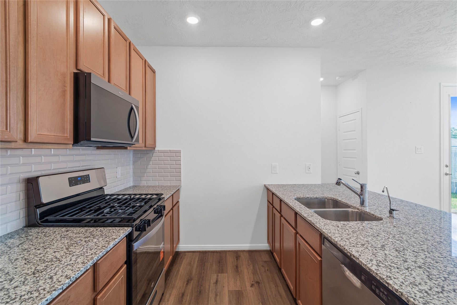 640 Appaloosa Meadow Drive, Magnolia, TX 77354 The kitchen features high ceilings, recessed lighting, Woodmont Cody cabinets in Toffee stain, granite countertops in Iberian White, SS appliances including microwave, and a pantry all overlooking your huge Great Room.