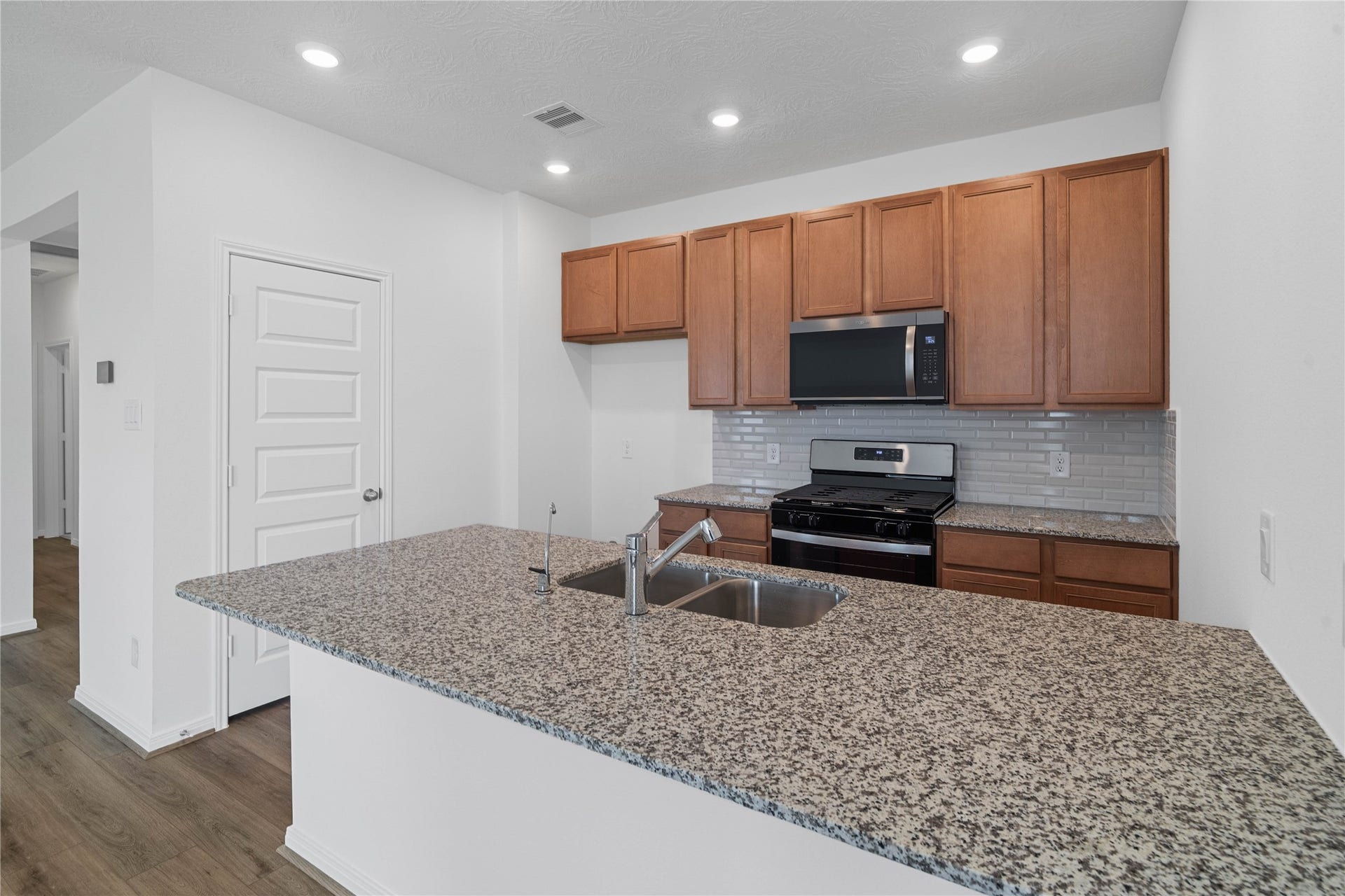 640 Appaloosa Meadow Drive, Magnolia, TX 77354 The kitchen exudes warmth with stunning Iberian White granite countertops perfectly paired with the rich, inviting tone of the Woodmont cabinetry in a Toffee stain. This combination creates a truly gorgeous and cohesive aesthetic.