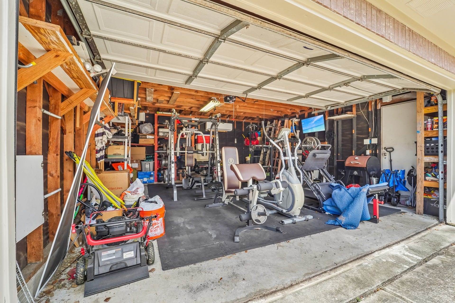 A spacious garage transformed into a versatile home gym, complete with various exercise equipment and ample storage space for tools and outdoor gear.