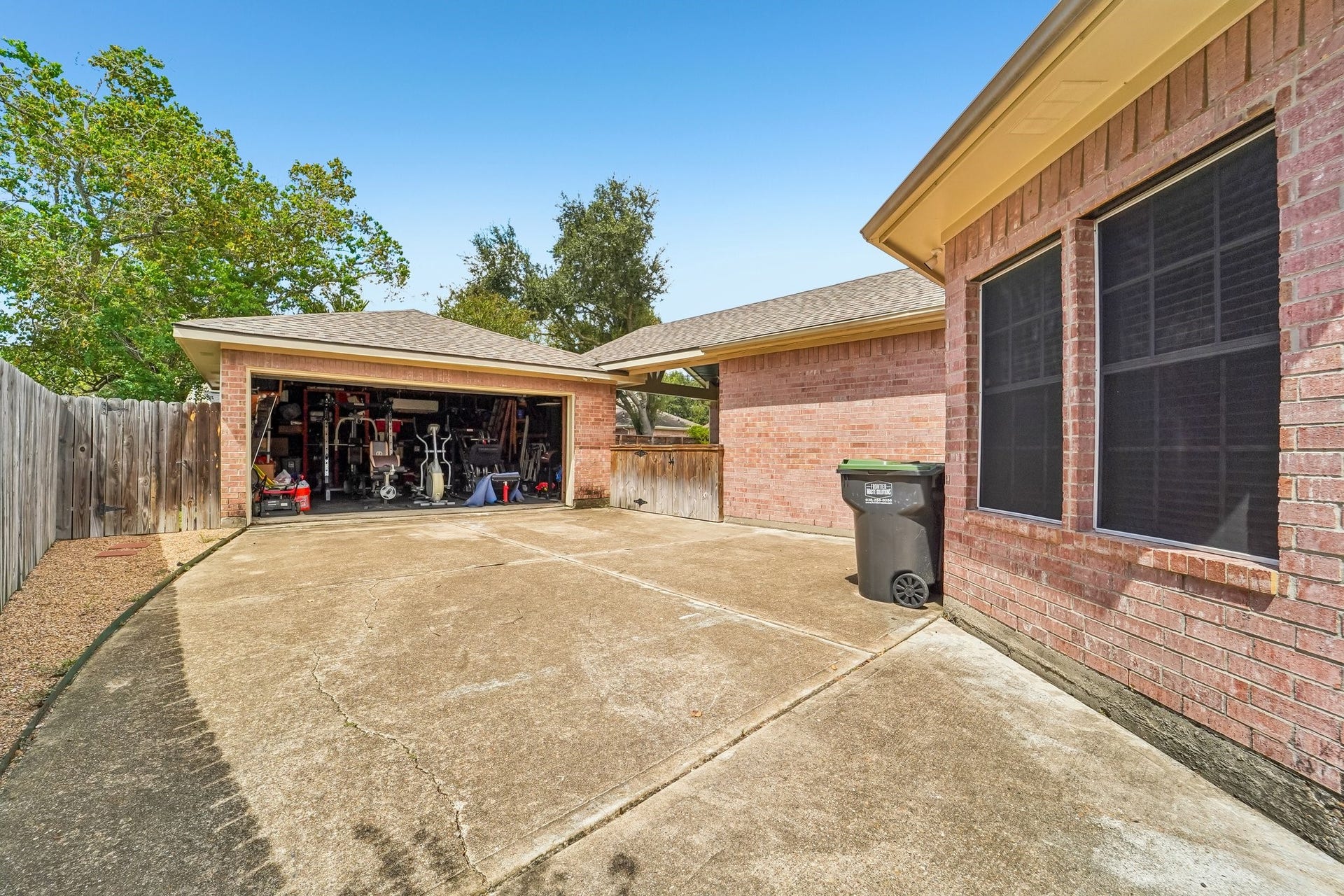 Spacious driveway leading to a detached two-car garage, perfect for storage or a workshop, surrounded by a privacy fence and mature trees.
