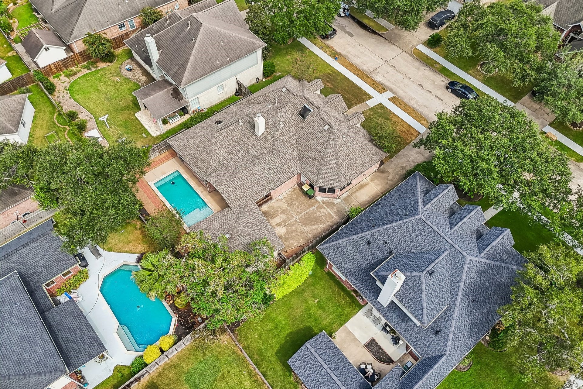 Spacious property featuring a large backyard with a refreshing pool, ideal for entertaining and relaxation, nestled in a charming neighborhood with lush greenery.