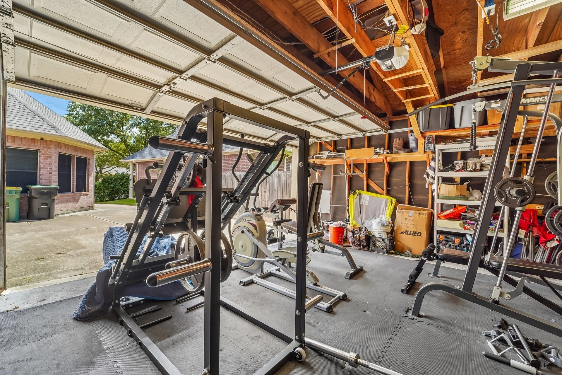 Spacious garage converted into a functional home gym, featuring a variety of exercise equipment and ample storage, perfect for fitness enthusiasts.