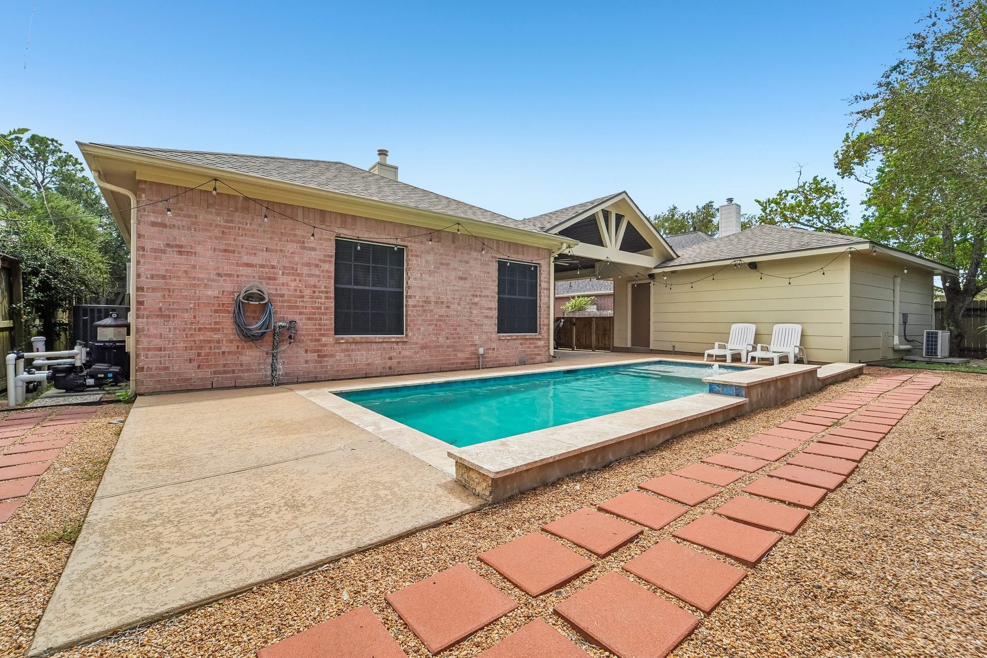Charming backyard oasis featuring a sparkling pool, spacious patio, and cozy seating area, perfect for relaxing or entertaining.