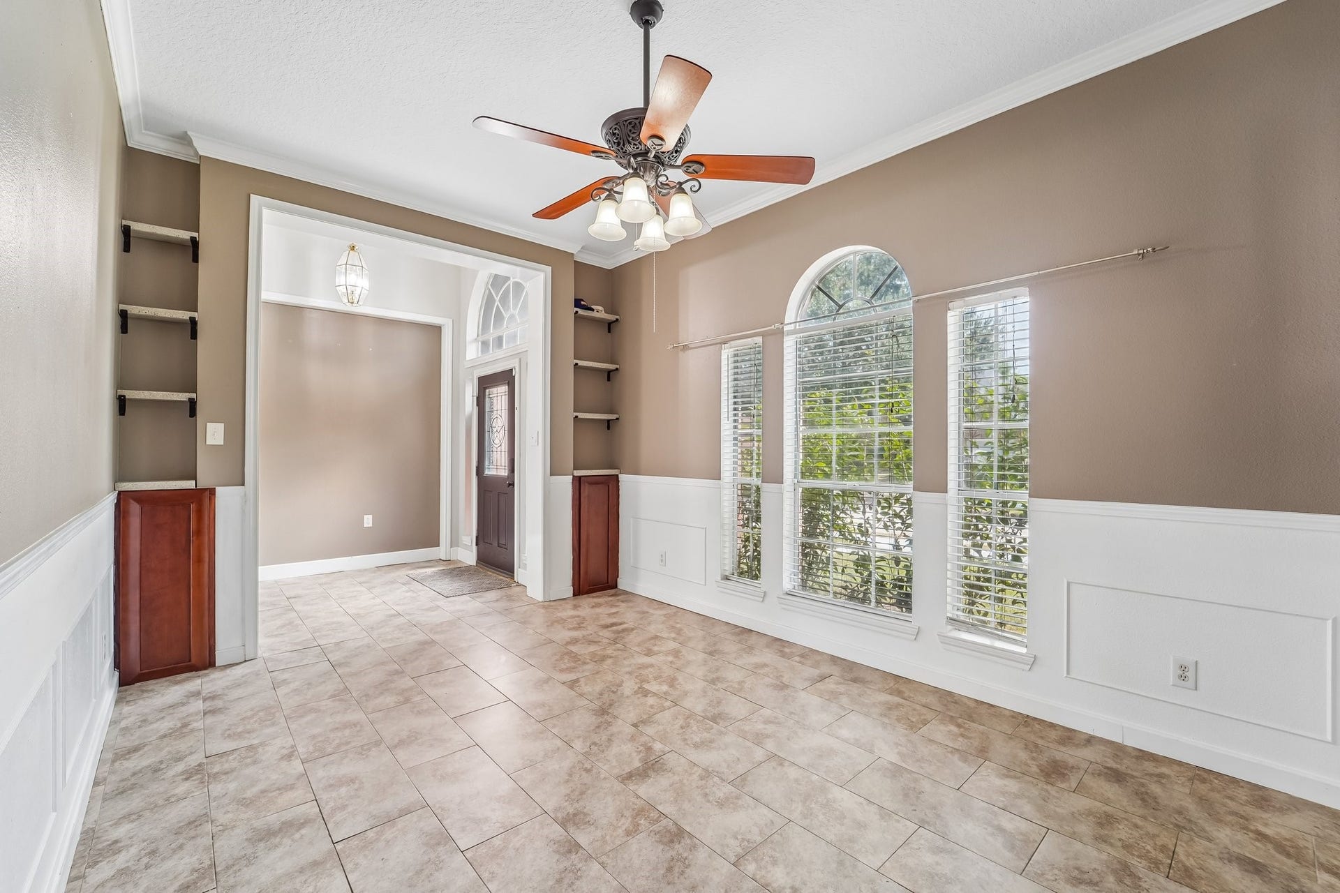 Bright dining area featuring large arched windows, elegant wainscoting, and stylish built-in shelving.