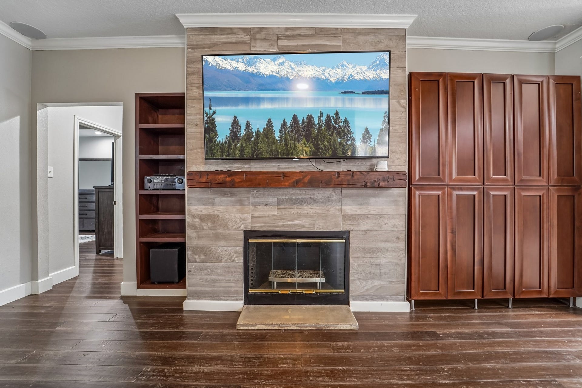 Elegant living area with a cozy fireplace, built-in shelving, and rich wood cabinetry, complemented by a wall-mounted TV.