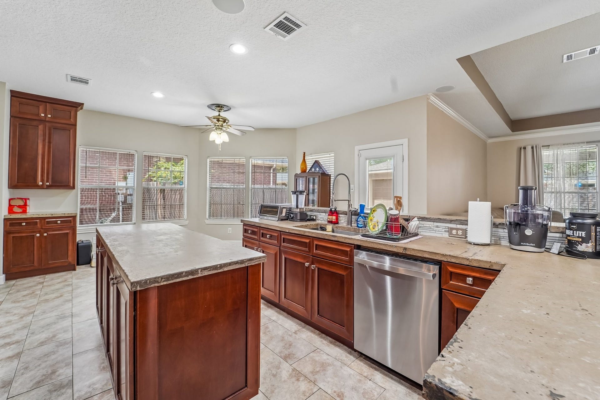 Spacious kitchen featuring elegant wooden cabinetry, a large central island, and modern stainless steel appliances, all enhanced by ample natural light from multiple windows.