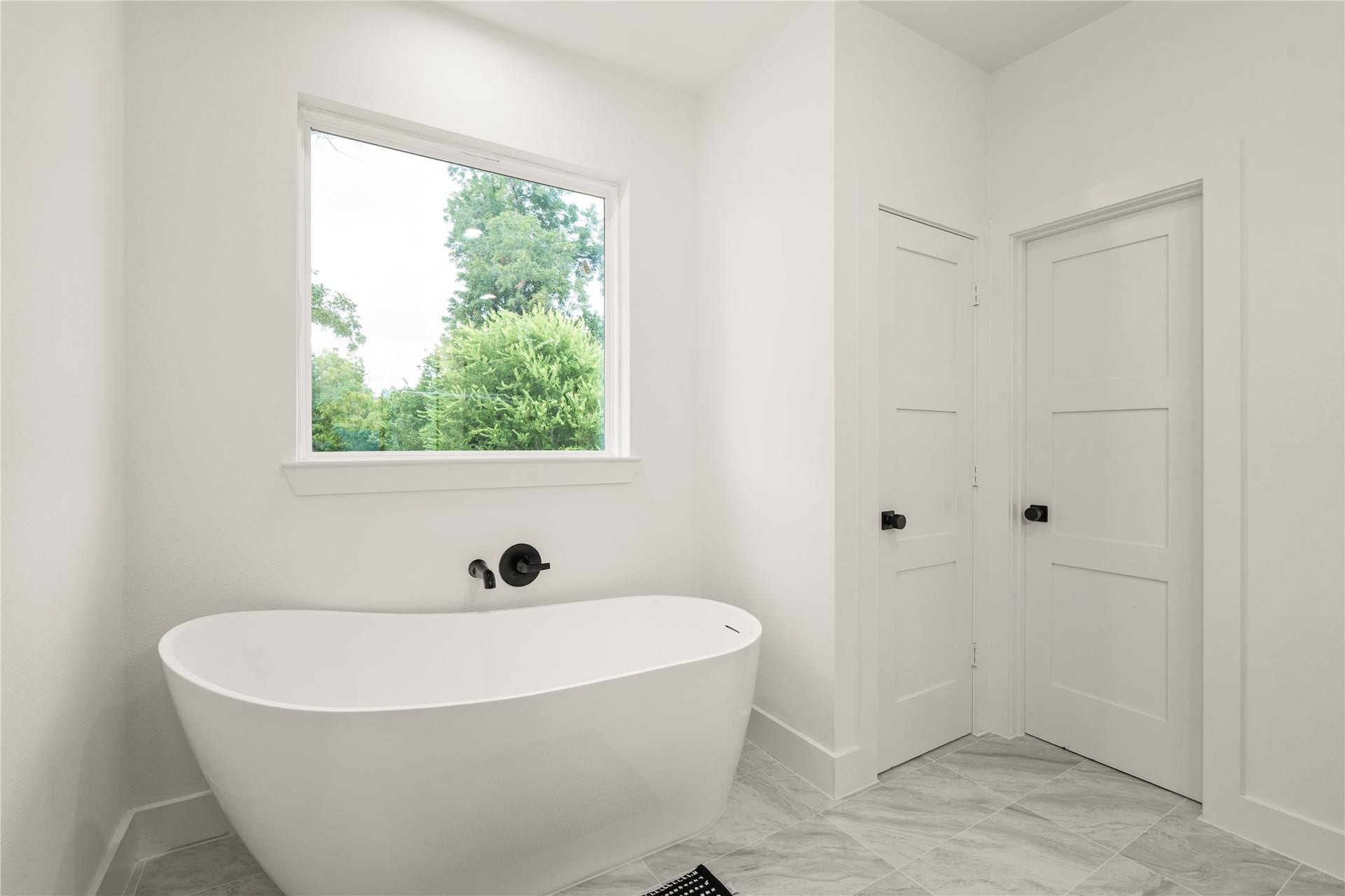 3412 Cortlandt Street, Houston, TX 77018 A sculptural freestanding soaking tub sits beneath a picture window framing mature treetops, paired with a
wall-mounted matte-black tub filler for a serene, spa-like moment at the end of the day.