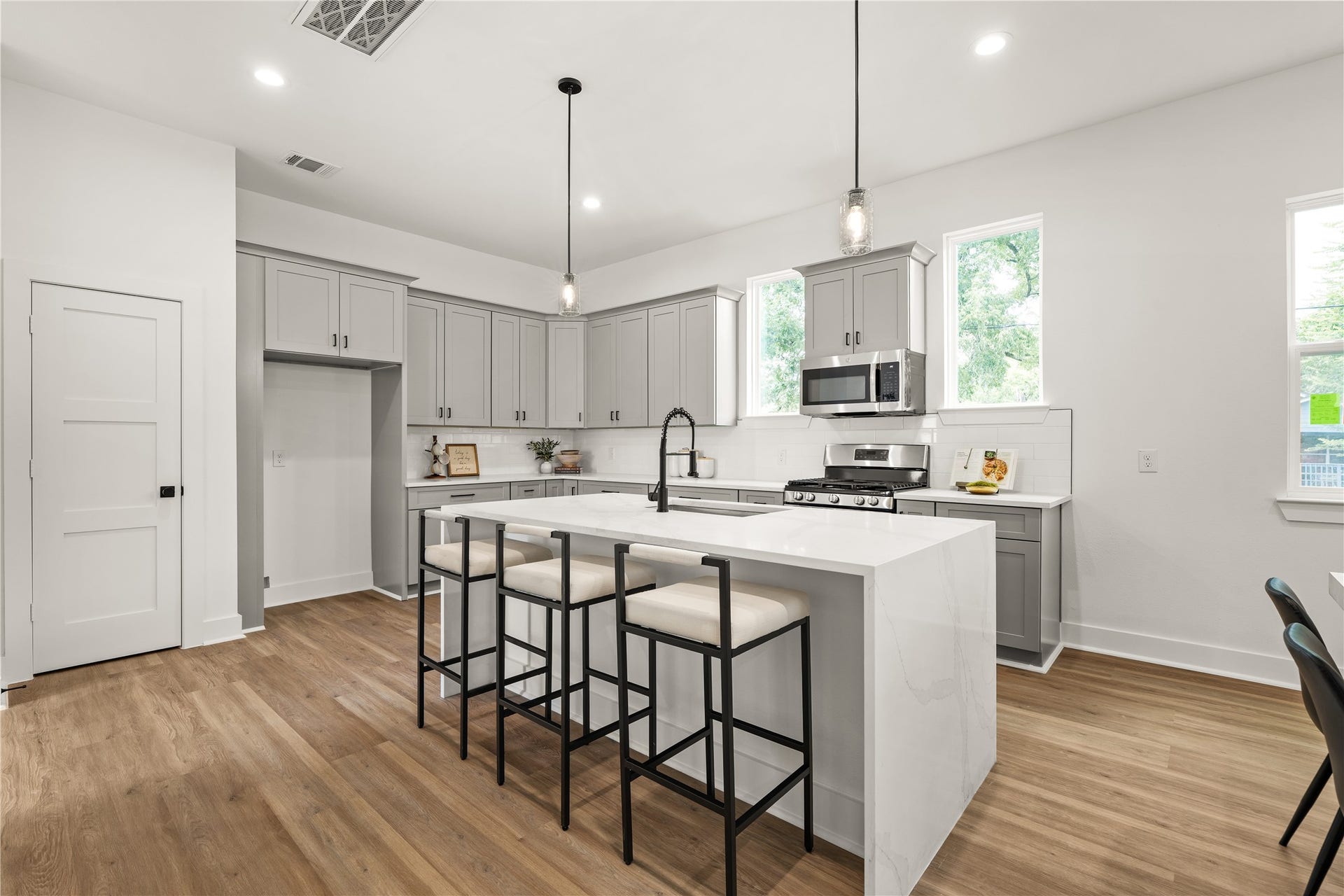 3412 Cortlandt Street, Houston, TX 77018 The kitchen makes an immediate statement with a waterfall-edge island, gray Shaker cabinetry with
matte-black hardware, and seeded-glass pendants, creating a natural centerpiece for cooking, gathering, and
lingering.
