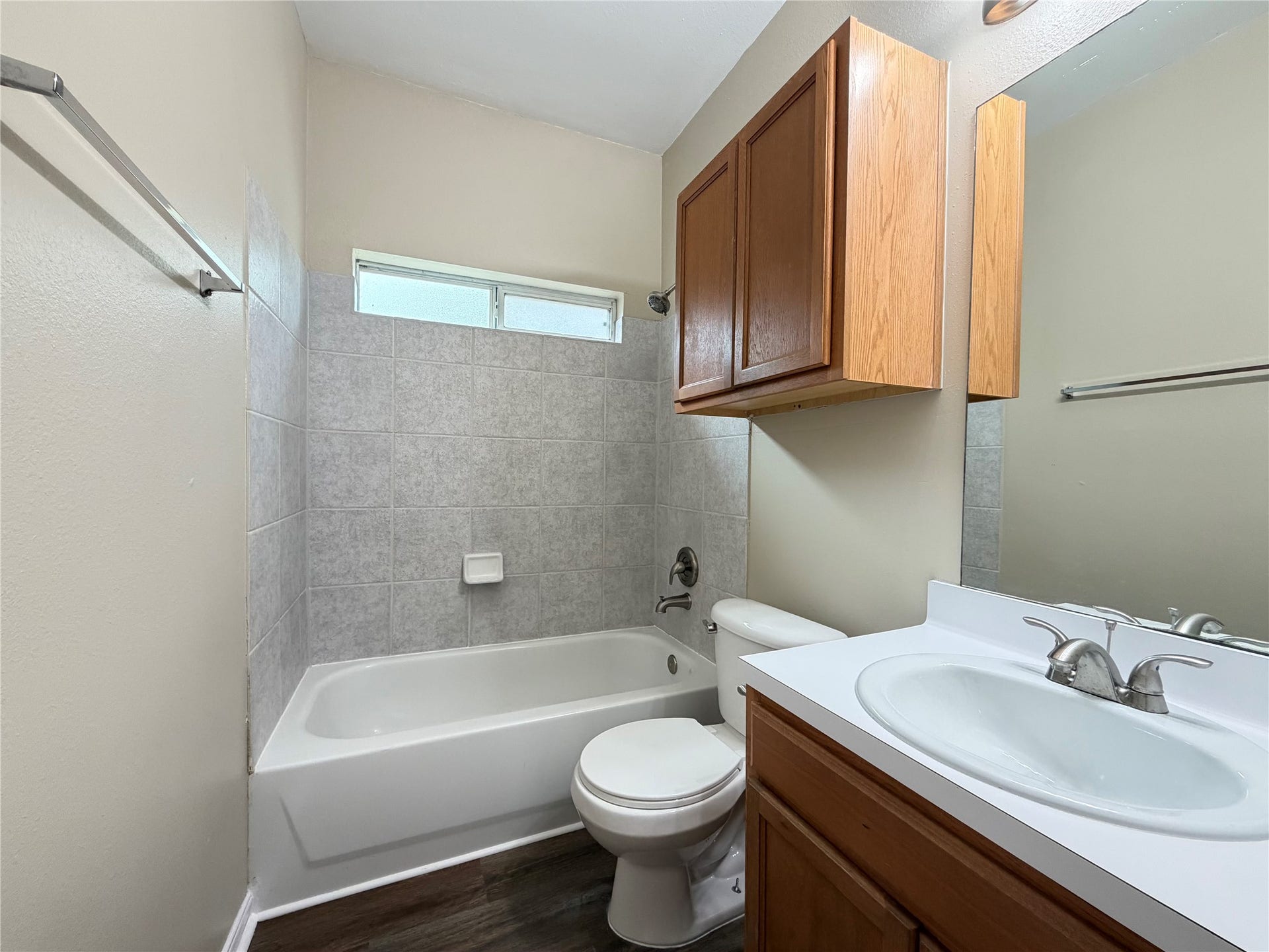 Charming second bathroom featuring a sleek tub, elegant tilework, and ample storage with wooden cabinetry, offering both style and functionality.