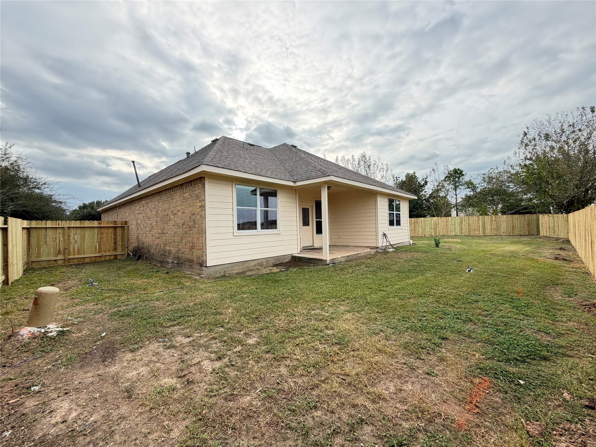 Charming backyard with a spacious lawn, new privacy fence, and a cozy covered patio perfect for relaxing or entertaining. Home backs up to green space.
