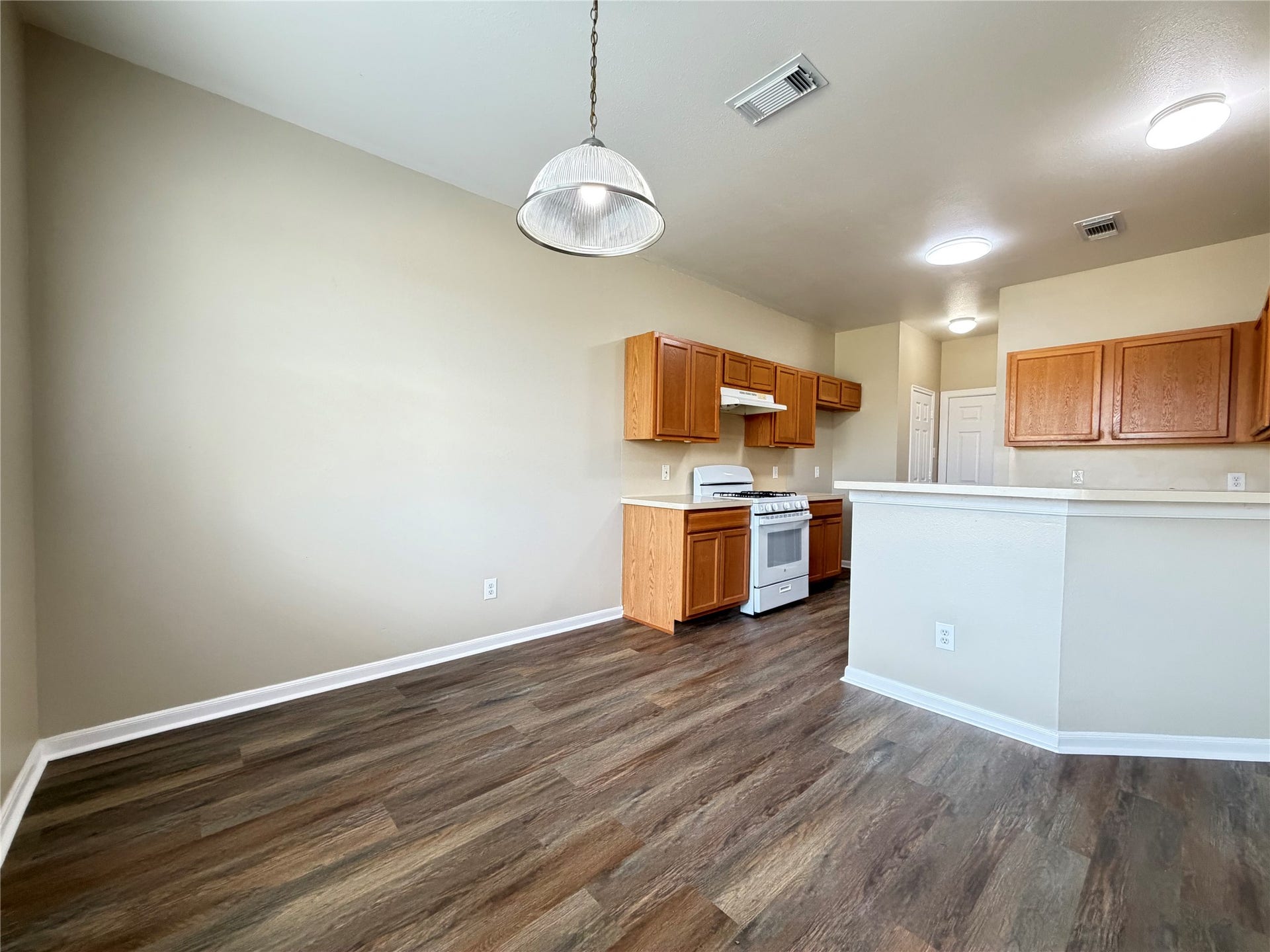 Spacious kitchen with warm wood cabinets, modern lighting, and sleek flooring perfect for entertaining.