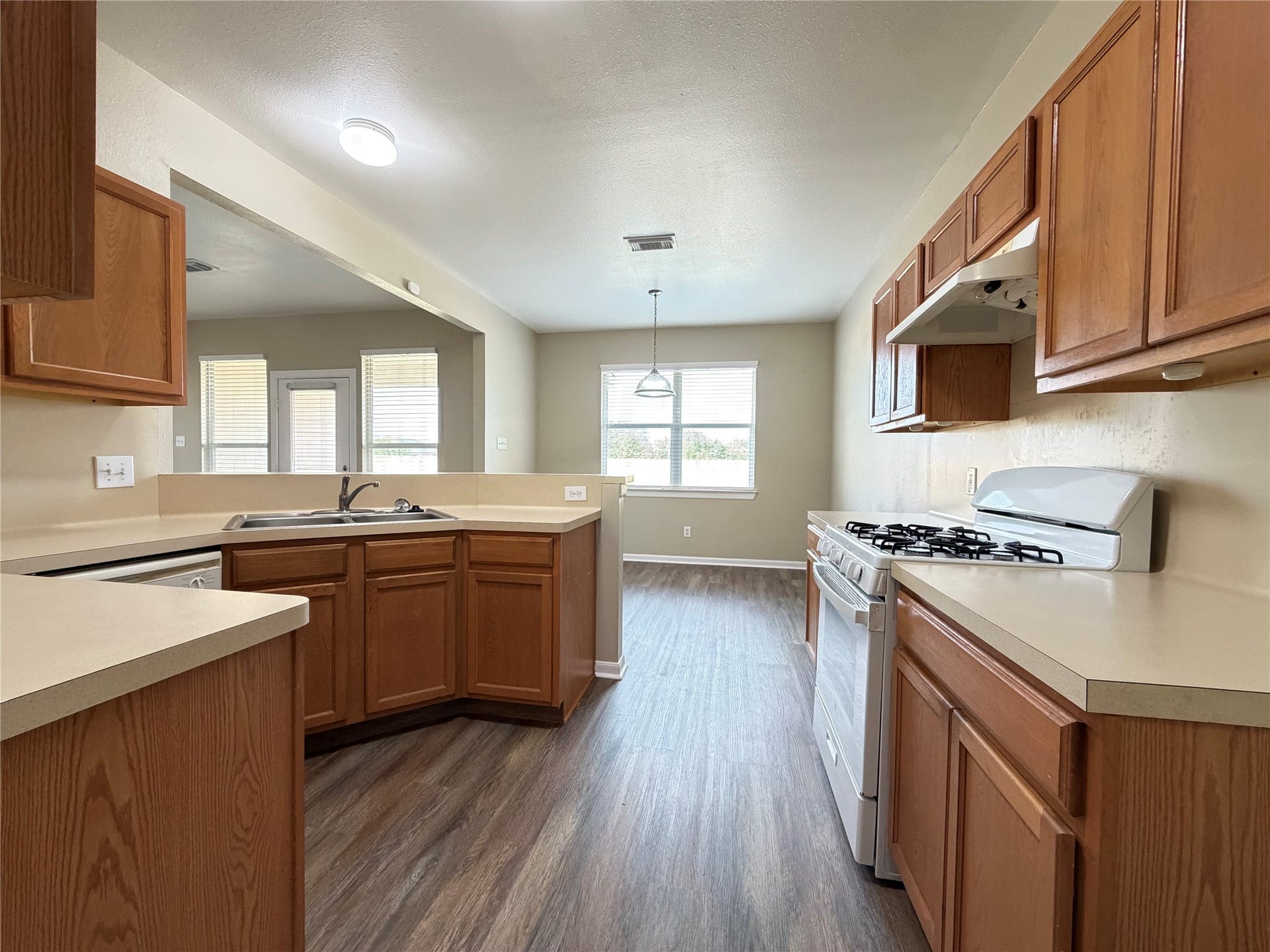 Bright and inviting kitchen with ample natural light, featuring wooden cabinetry, a gas stove, and a spacious layout perfect for meal prep and gatherings.