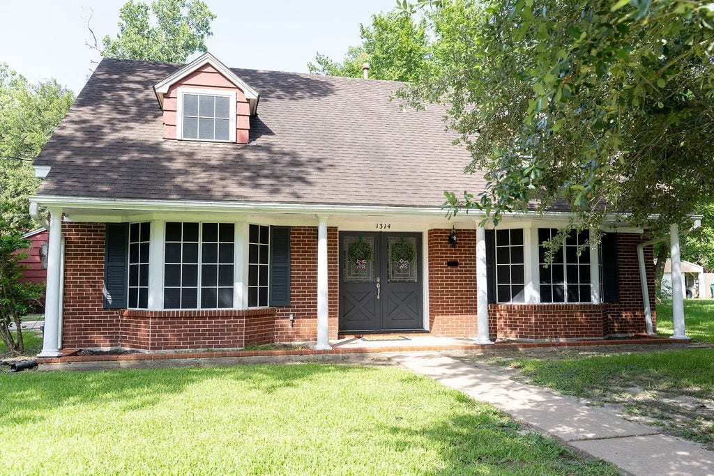 1314 Laurel Street, La Marque, TX 77568 Charming two-story brick home with a gabled roof and dormer window. Features a welcoming front porch, large windows, and a well-maintained lawn, framed by mature trees.