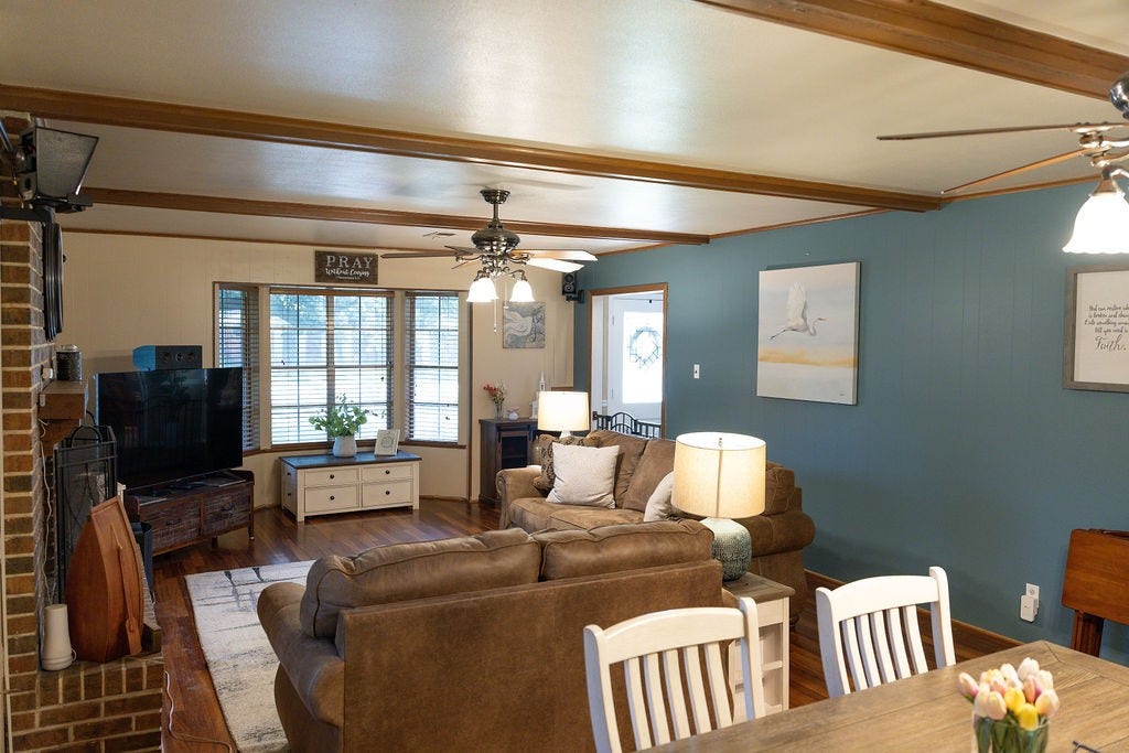 1314 Laurel Street, La Marque, TX 77568 This spacious family room and dining room combination showcases rich accent walls and beautifully stained faux wood beams, adding warmth, character, and a custom designer touch. It's the perfect blend of timeless elegance and comfortable living, creating an inviting space for entertaining or relaxing with family.
