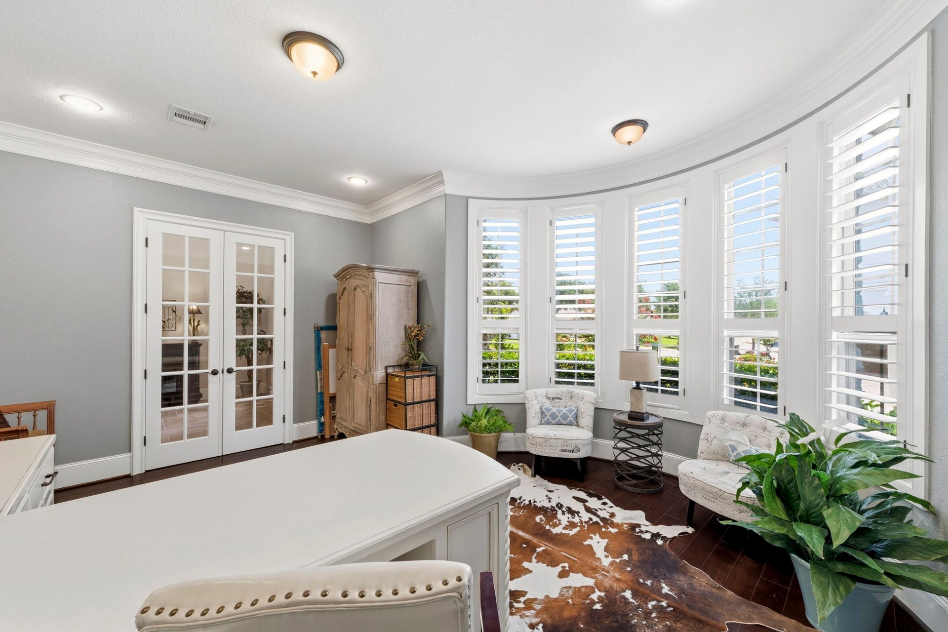 Beautiful Home Office featuring built in shelves, double sided desk, crown moulding and plantation shutters!