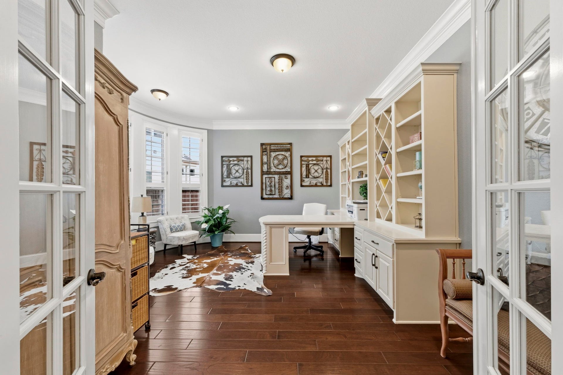 Beautiful Home Office featuring built in shelves, double sided desk, crown moulding and plantation shutters!