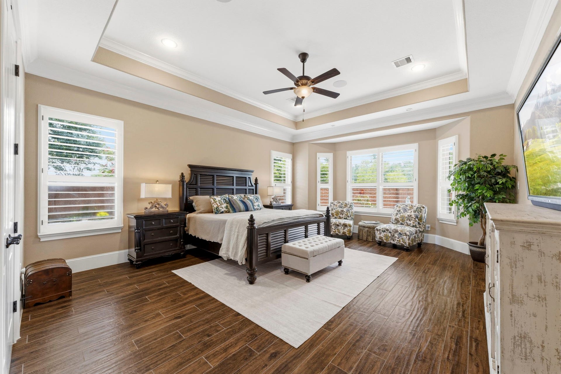 Primary Bedroom features tray ceiling, crown moulding and plantation shutters