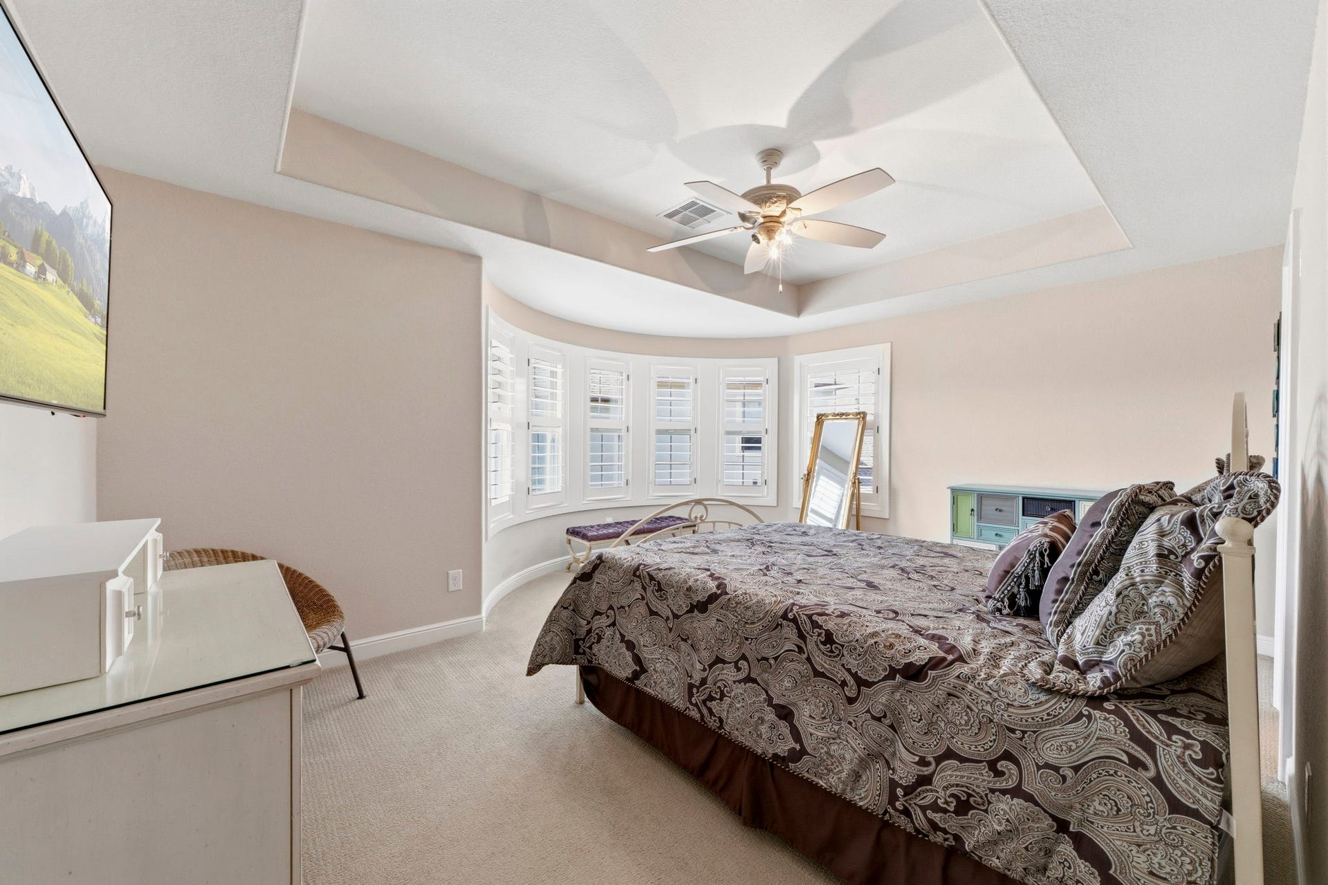 Secondary Bedroom upstairs has beautiful curved wall of windows with plantation shutters and an en-suite bath