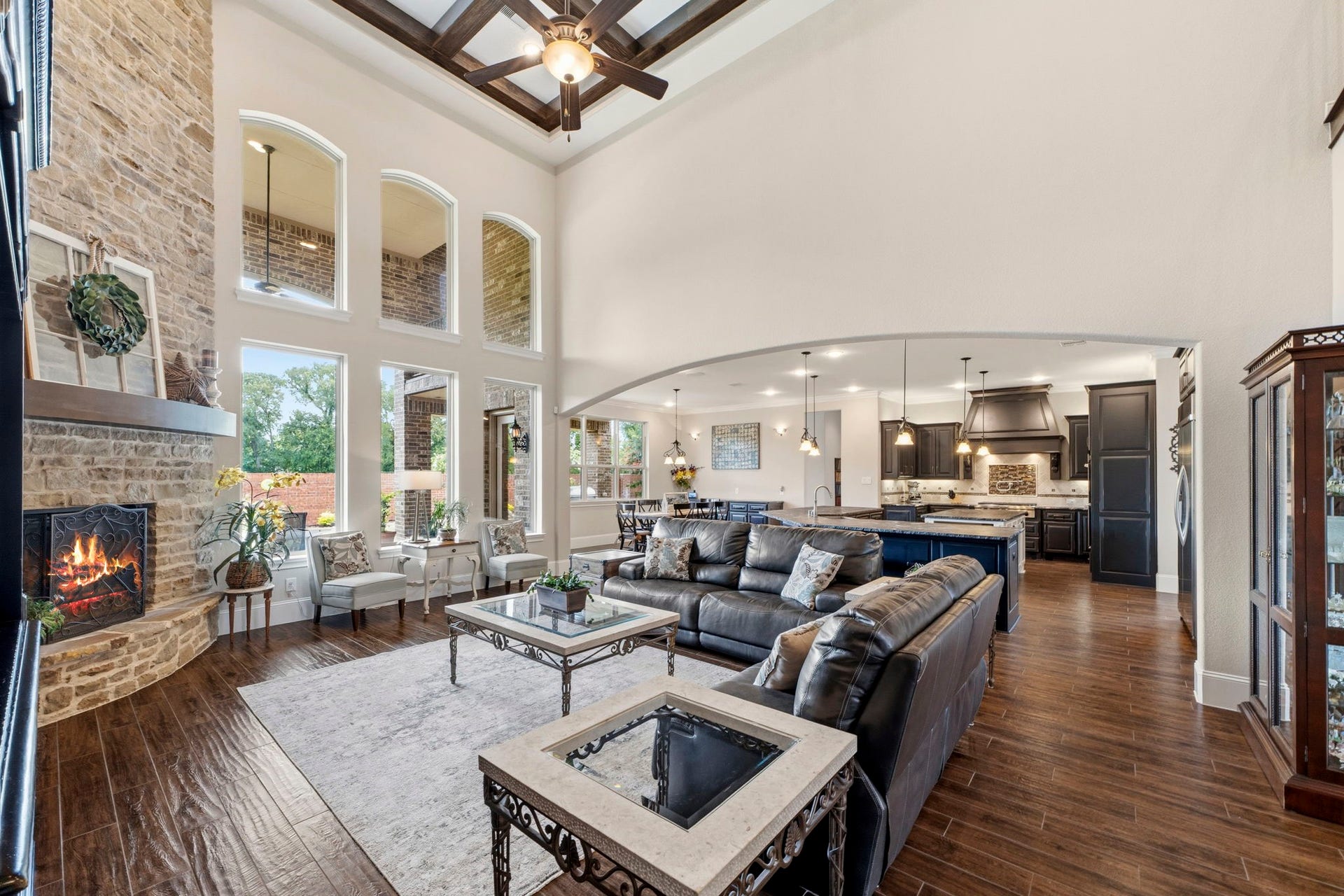 Grand Living Room with a stone fireplace that reached the coffered ceiling! Walls of windows allow natural light to cascade throughout