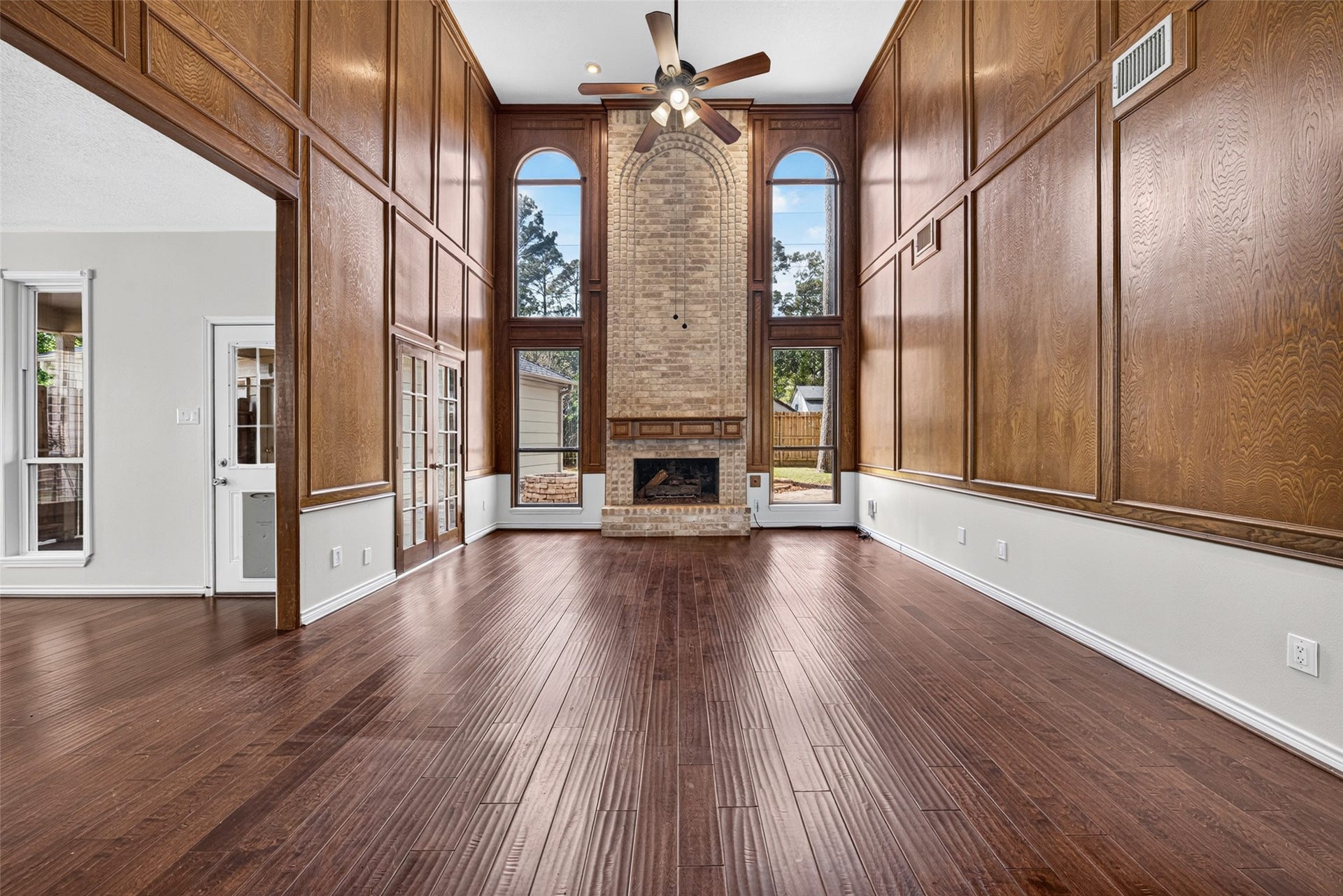 6206 Willow Pine Drive, Spring, TX 77379 Stunning living room with soaring ceilings, rich wood paneling, and a beautiful brick fireplace framed by large arched windows which flood the space with natural light.