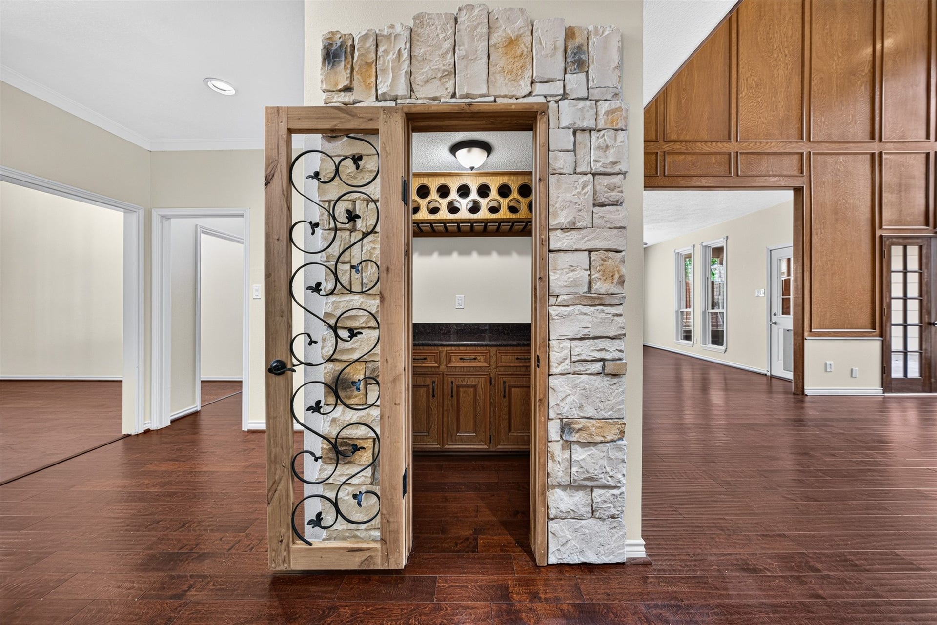 6206 Willow Pine Drive, Spring, TX 77379 Elegant wine cellar with a rustic stone and wood design, featuring wrought iron detailing and ample storage, seamlessly connected to entertaining spaces.