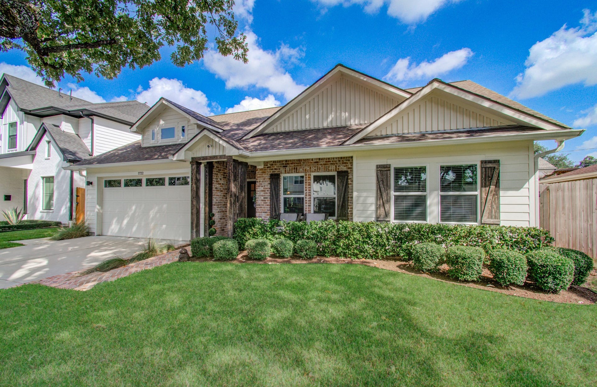 Charming single-story home with a welcoming front porch, manicured landscaping, and an attached garage.