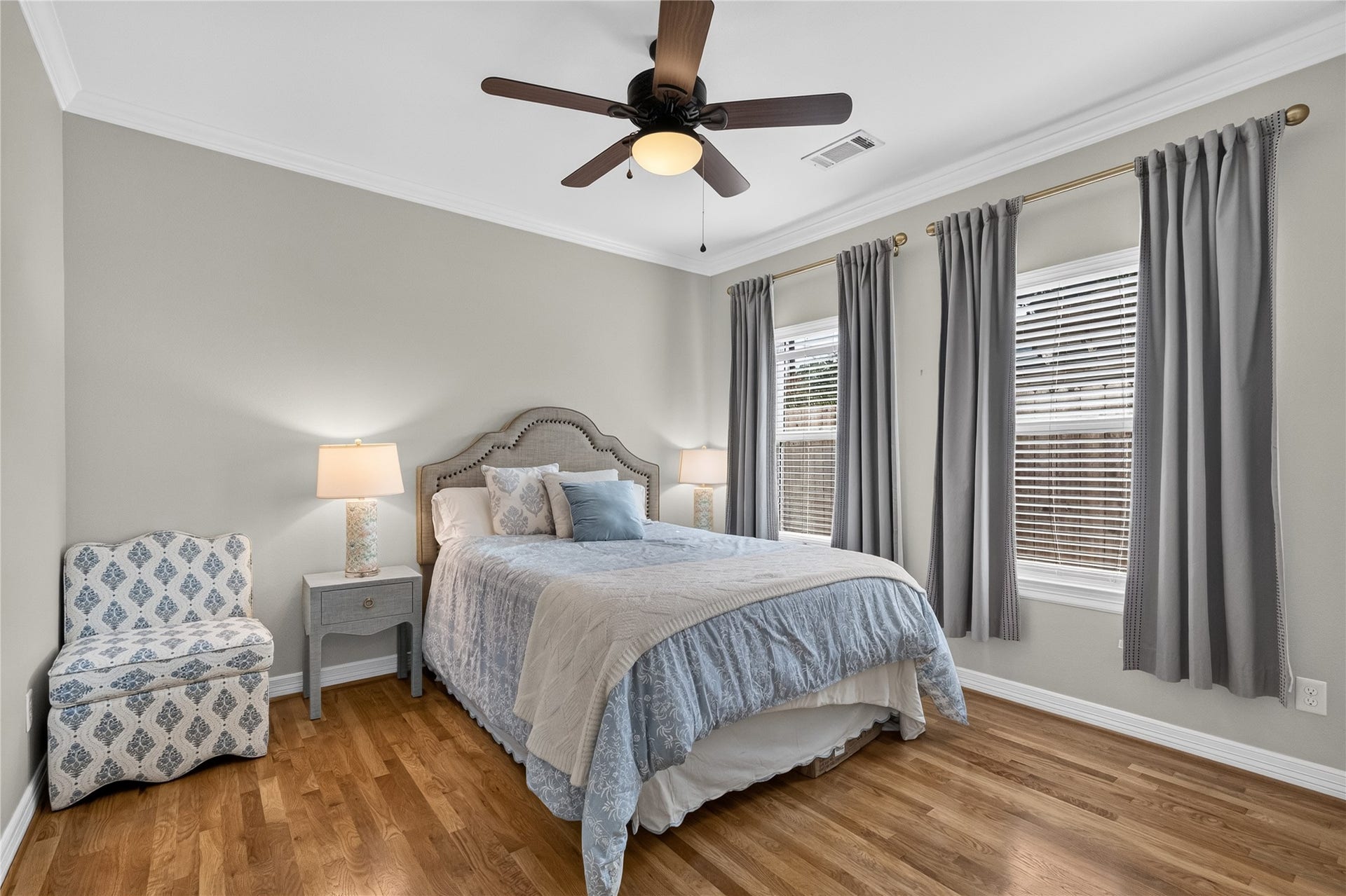Cozy third bedroom featuring hardwood floors and ample natural light from two large windows.