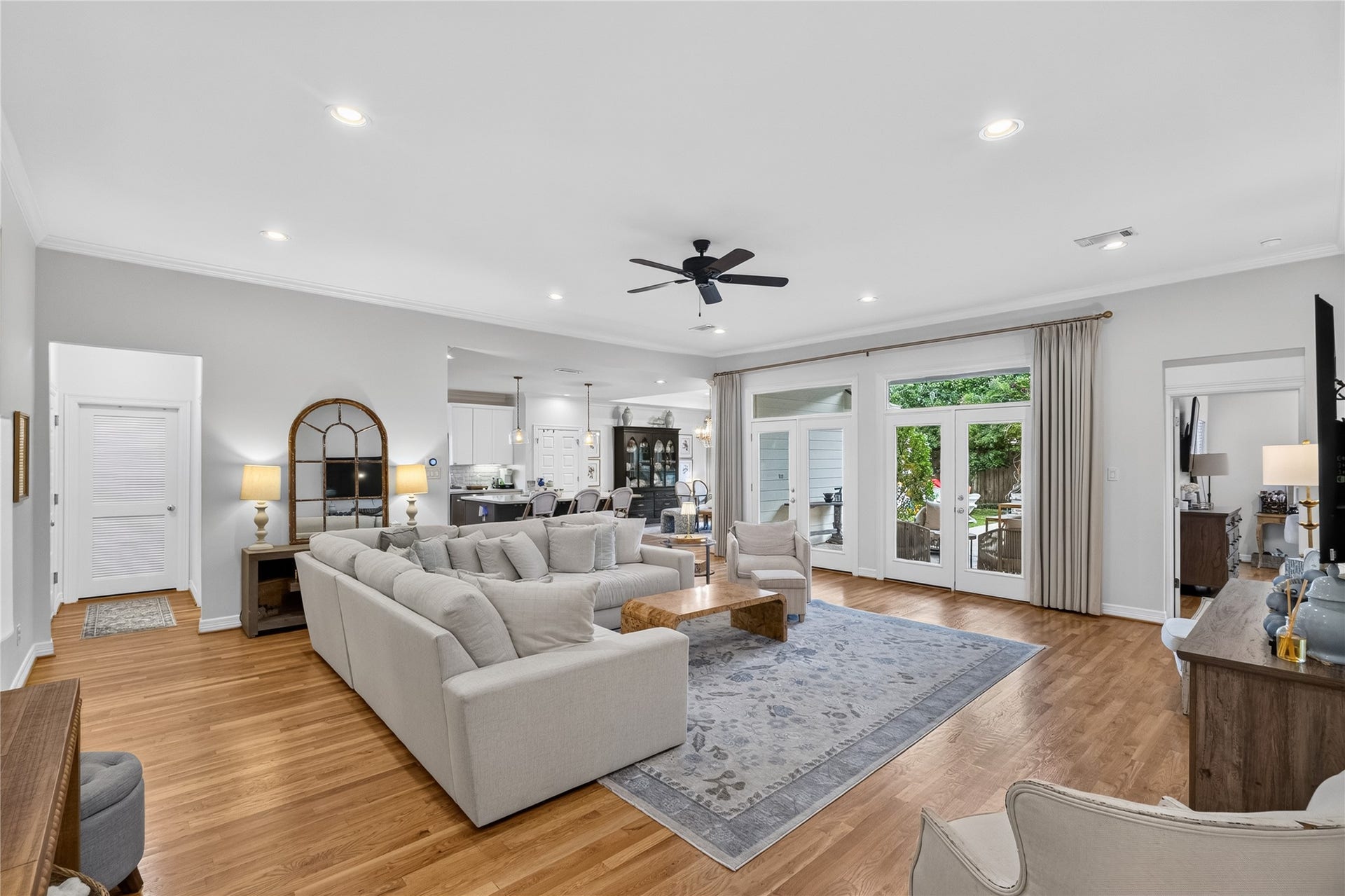 Spacious and inviting living area with elegant hardwood floors, abundant natural light from large French doors, and a seamless flow into the modern kitchen.