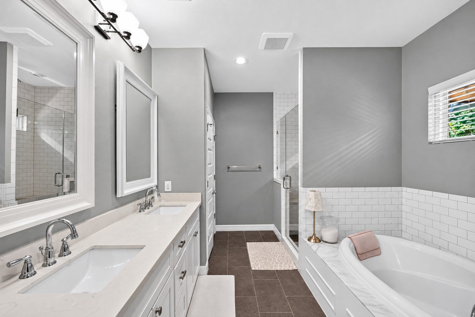 Elegant primary bathroom featuring a spacious dual-sink vanity, luxurious soaking tub, and a glass-enclosed shower, all enhanced by modern lighting and sleek tile accents.