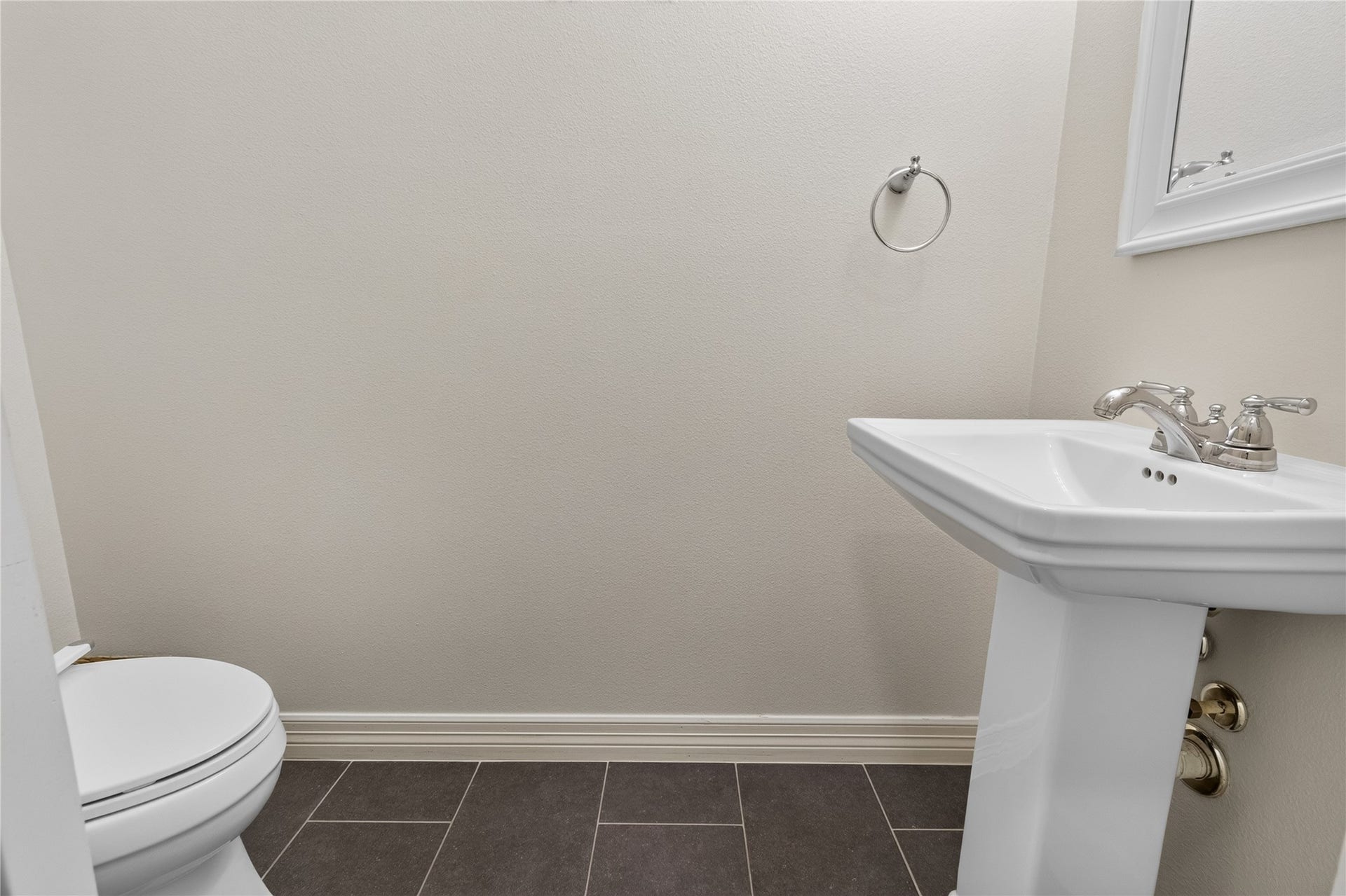 Charming powder room featuring a sleek pedestal sink, modern fixtures, and elegant tile flooring for a clean, minimalist look.