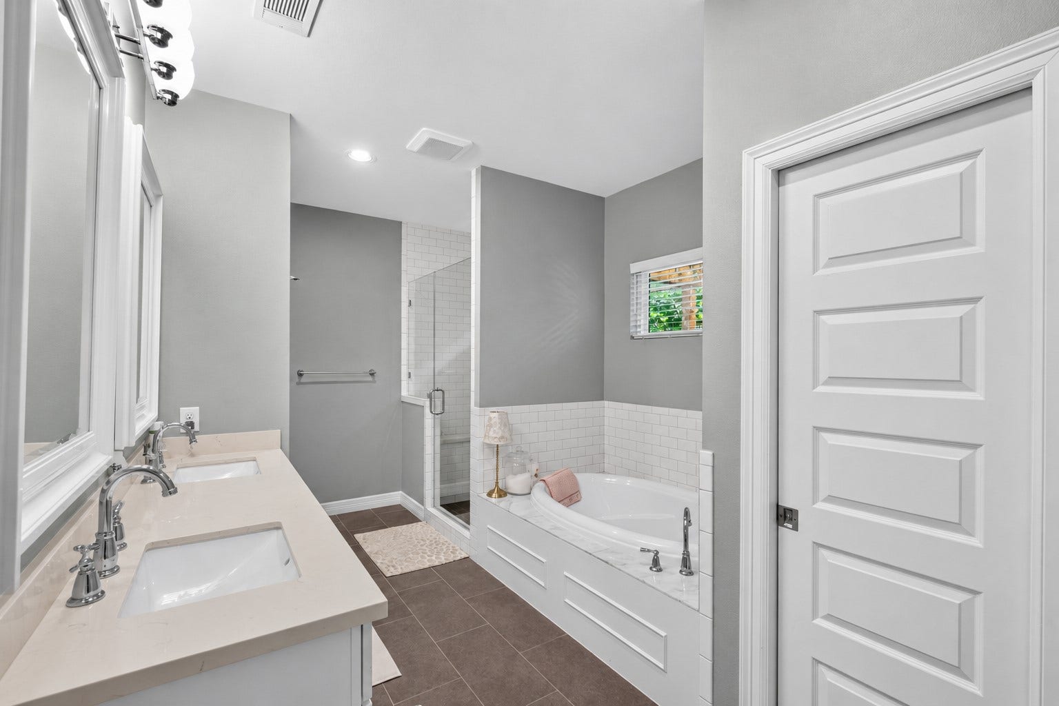 Elegant primary bathroom featuring a dual-sink vanity, spacious glass-enclosed shower, and a luxurious soaking tub, all accented by contemporary fixtures and a neutral color palette.