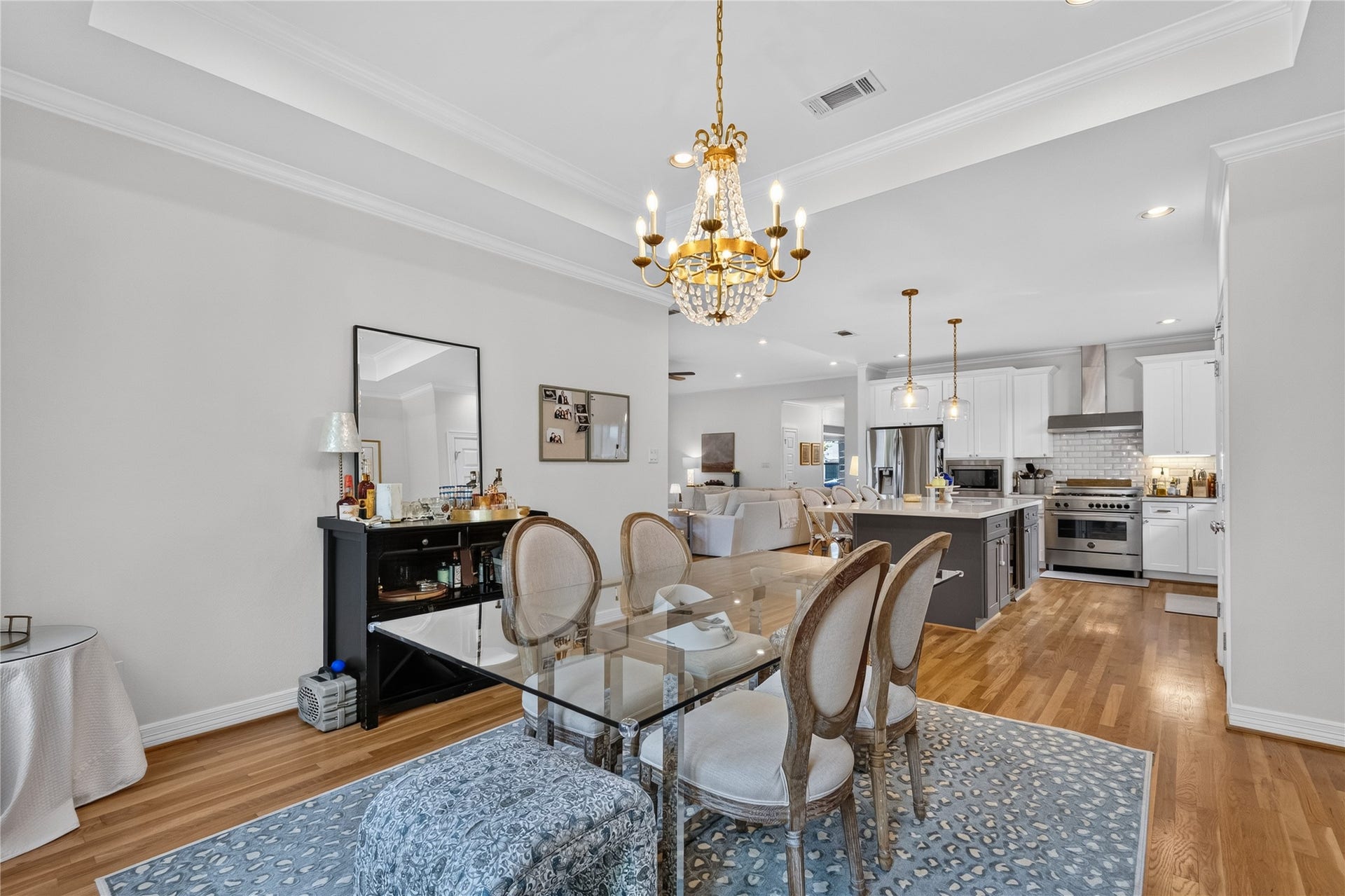 Elegant dining area with crown molding enhanced by a stunning chandelier overhead. The open layout seamlessly connects to a modern kitchen featuring stainless steel appliances and a spacious island, perfect for entertaining.