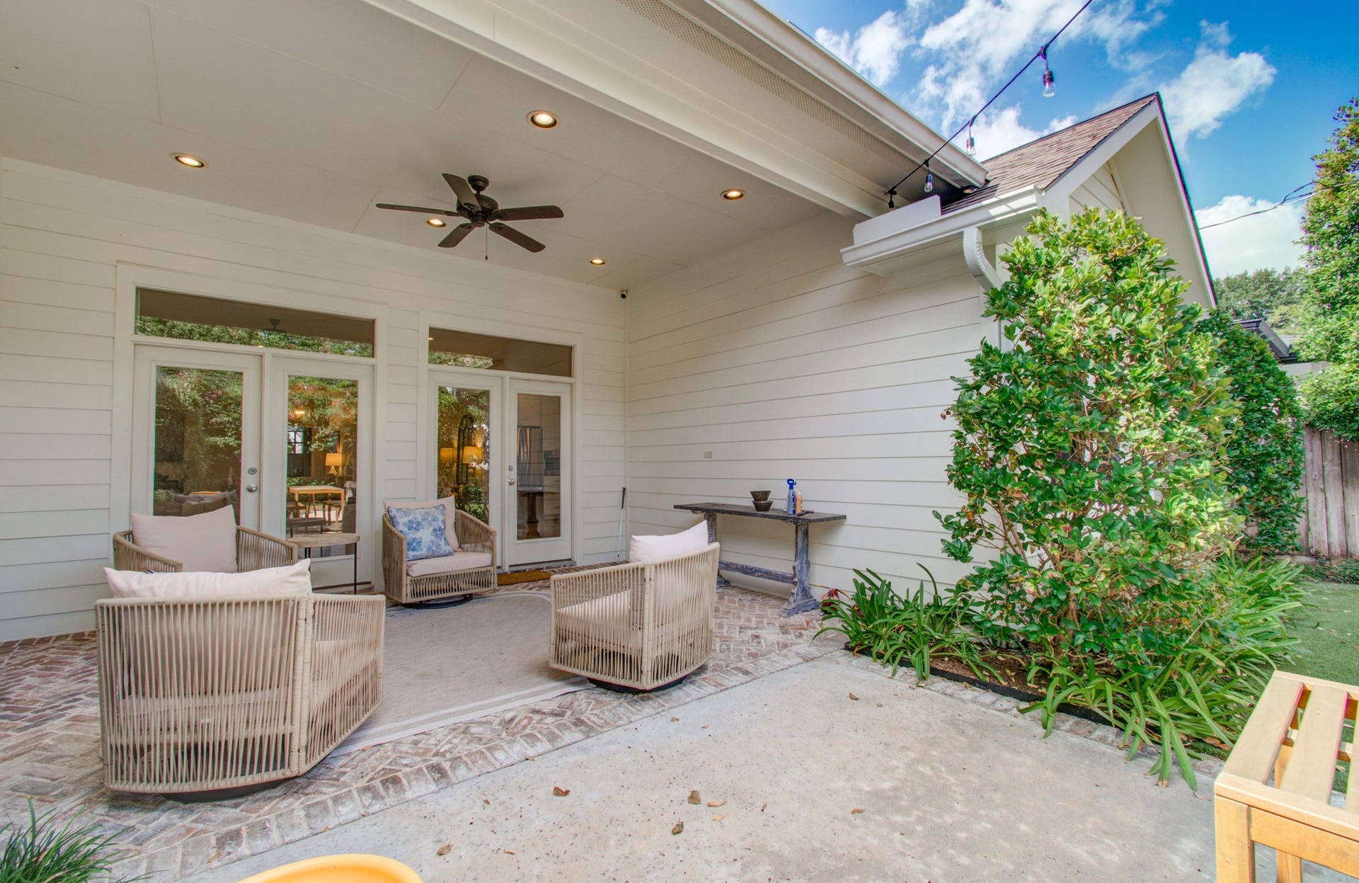 Charming covered patio with comfortable seating and ceiling fan, perfect for outdoor relaxation and entertaining.