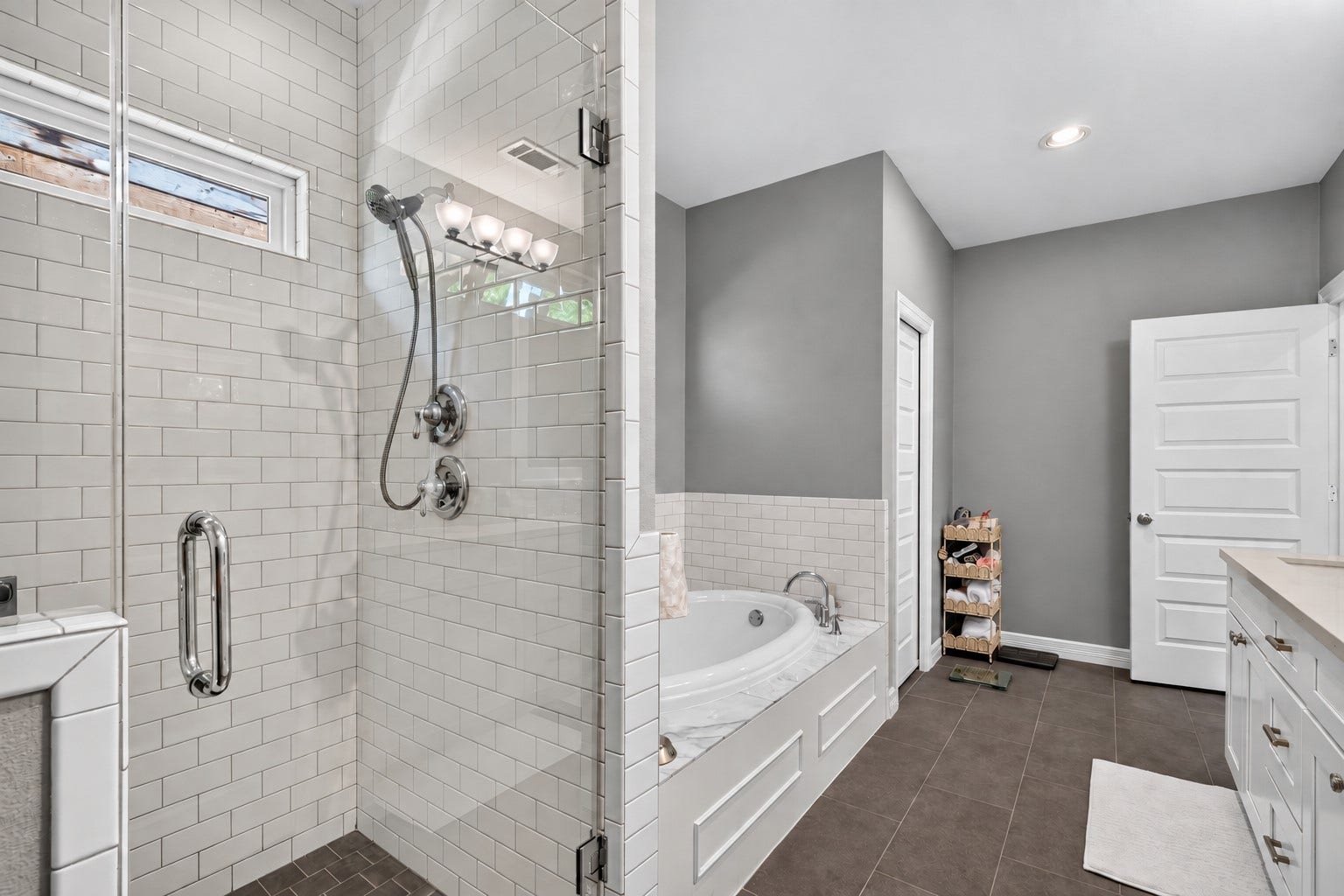 Stylish bathroom featuring a spacious glass-enclosed shower with subway tile, a relaxing soaking tub, and modern fixtures.