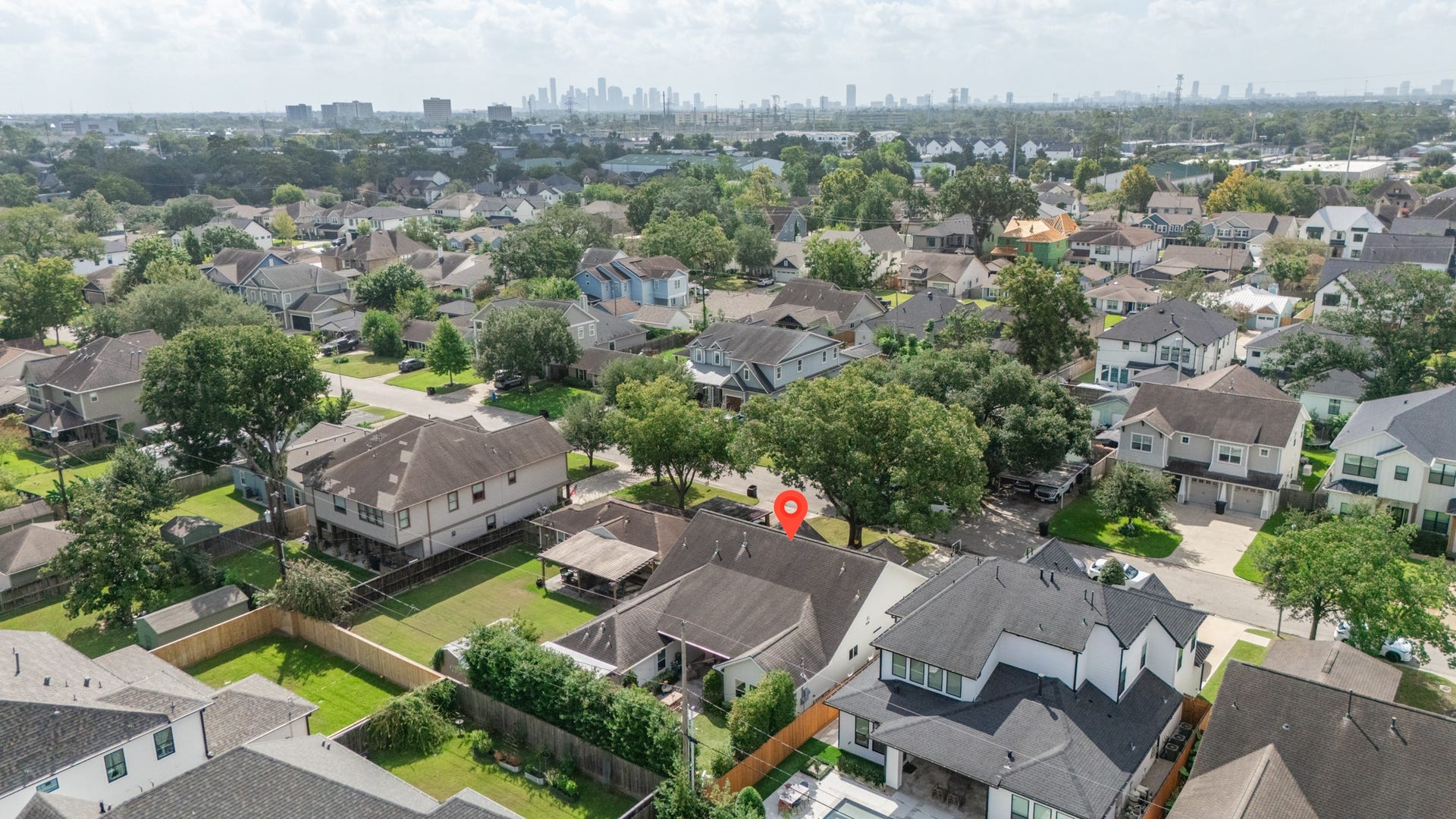 Charming suburban neighborhood with tree-lined streets and a mix of modern and traditional homes, offering city skyline views in the distance.