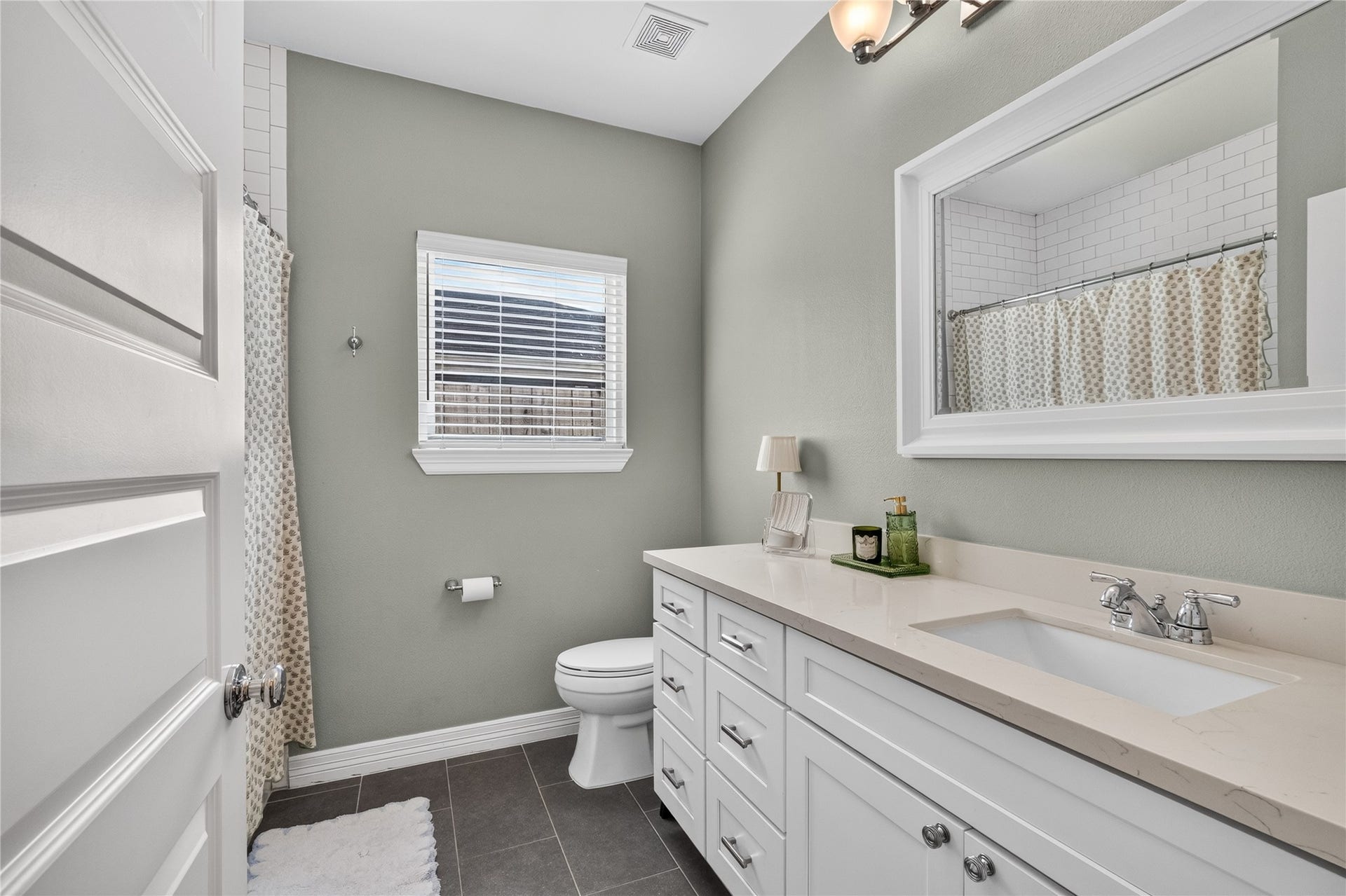Bright and inviting secondary bathroom featuring a sleek vanity with ample storage, modern fixtures, and a soothing color palette.