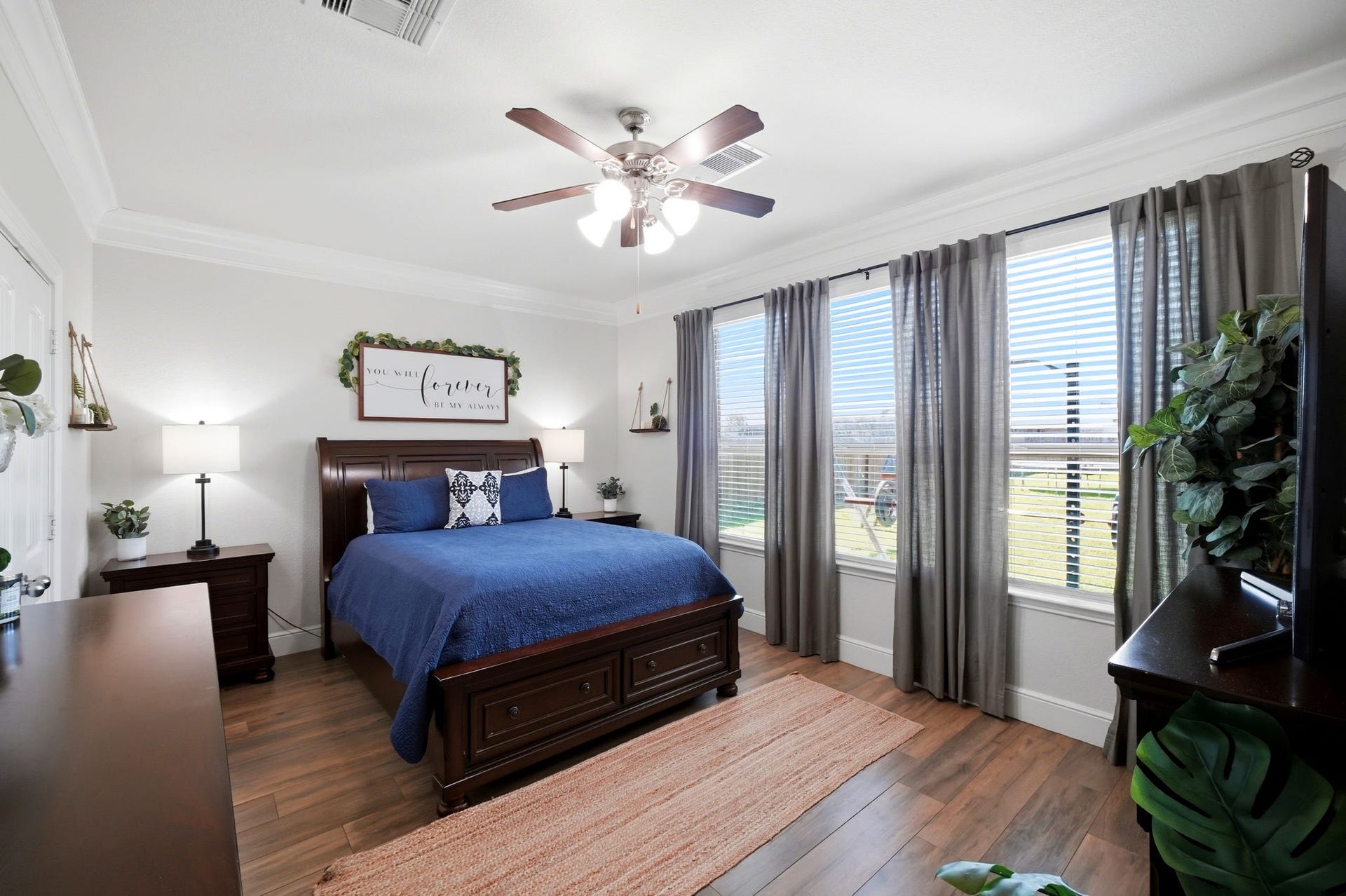 21639 Lexor Drive, Porter, TX 77365 Bright and inviting bedroom with large windows offering serene views, featuring elegant flooring, a ceiling fan, and tasteful decor.