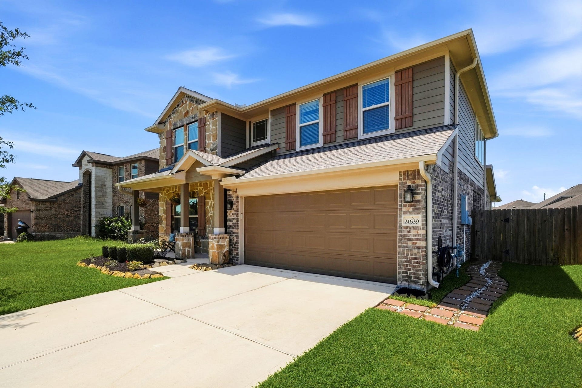 21639 Lexor Drive, Porter, TX 77365 Charming two-story home with stone accents and a spacious two-car garage, set amidst a well-maintained lawn and a cozy front porch perfect for relaxation.