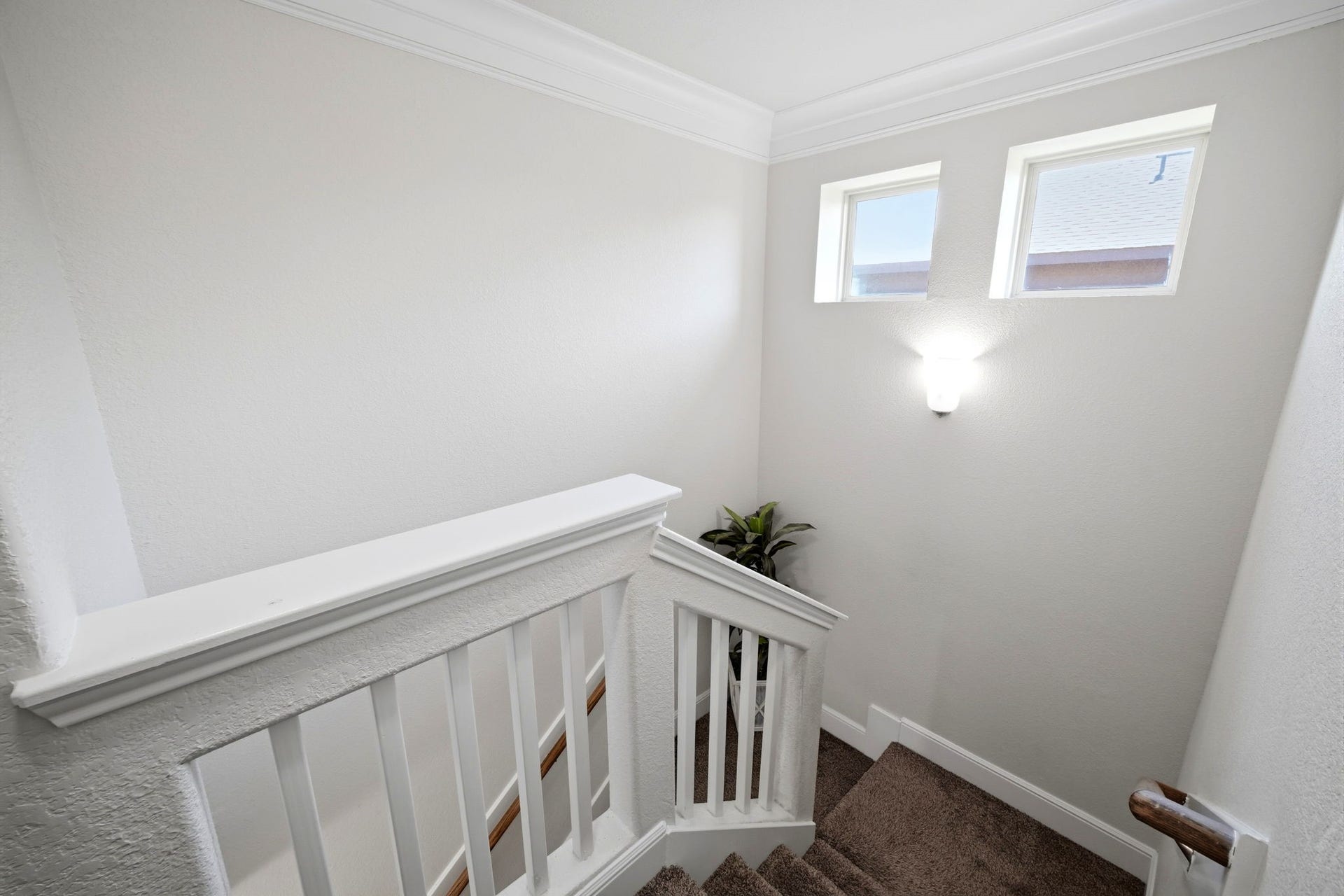 21639 Lexor Drive, Porter, TX 77365 Bright and inviting staircase with plush carpeting, modern wall sconces, and ample natural light from two upper windows.
